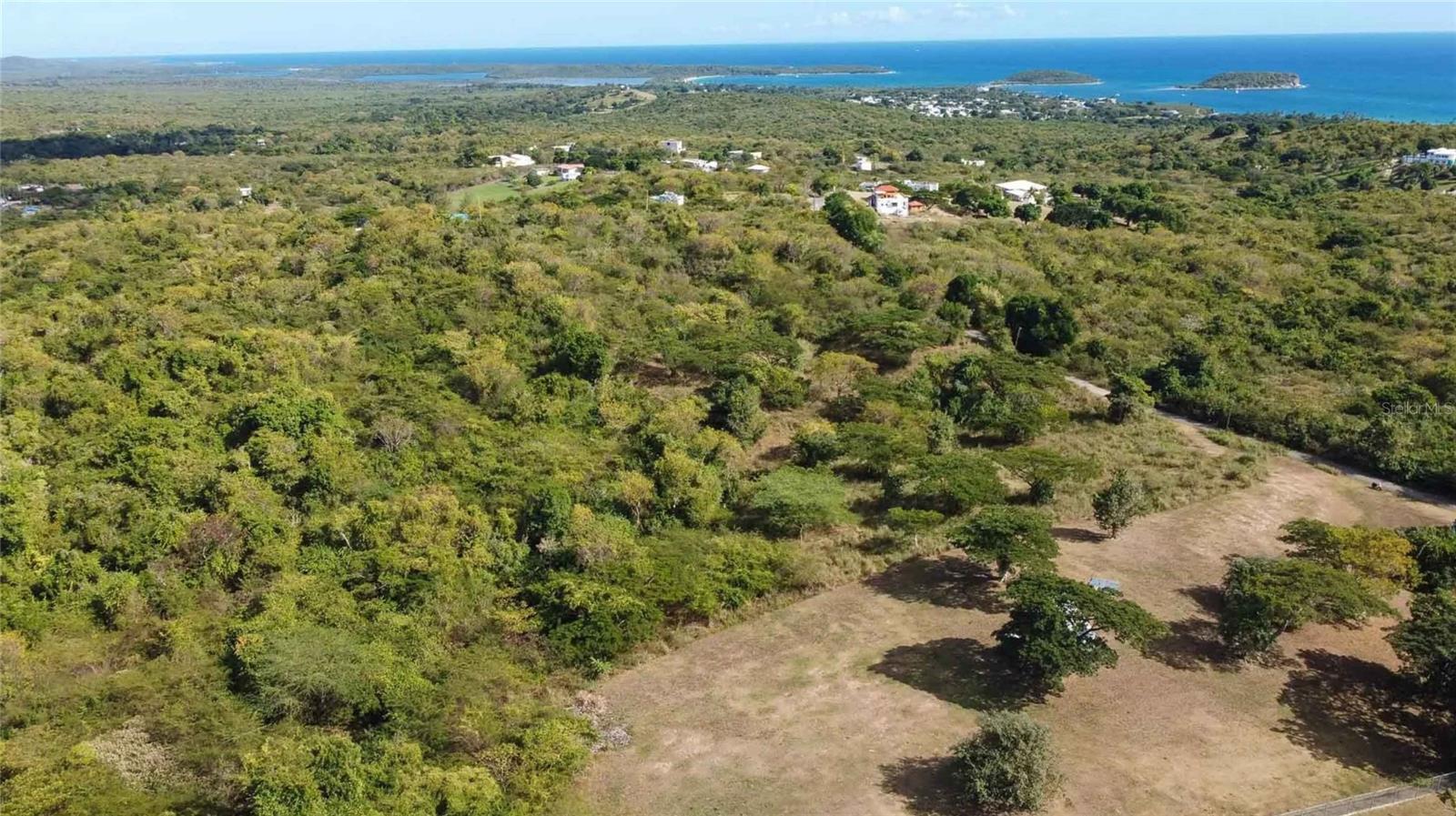JB’s La Llave Lot, a rare opportunity to acquire a 2.5-acre parcel in one of Vieques Island’s most desirable neighborhoods. Located in the peaceful and established La Llave area, this property offers mature trees, gently rolling hills, southern ocean views, and a convenient location close to Black Sand Beach, Esperanza, and Sun Bay.

This is one of the few remaining parcels of this size in La Llave. The lot includes road frontage with direct access to the La Llave road, which simplifies connections to municipal electric and water service. The land is currently undeveloped, giving buyers the freedom to design and build their ideal home. As a bonus, the property includes existing architectural plans for a two-story residence, included in the sale—an excellent head start for those ready to build.

The sloping terrain offers multiple elevated build sites and the potential for second-story views of the Caribbean Sea, particularly overlooking the Puerto Real area of southern Vieques. Mature trees provide shade and character throughout the acreage, while the topography lends itself to thoughtful landscaping and creative design. Whether you envision a full-time residence, vacation home, or investment property, this is a manageable yet spacious canvas with strong long-term potential.

The La Llave neighborhood is popular with both full-time residents and seasonal homeowners. Known for its quiet atmosphere, sea breezes, and close proximity to Vieques’ south shore beaches, La Llave offers the perfect balance of seclusion and accessibility. The world-famous Playa Negra (Black Sand Beach) is just down the road, and the vibrant seaside village of Esperanza—with its restaurants, shops, and waterfront promenade—is only a short drive away.

Vieques is home to some of the most unique and protected natural spaces in Puerto Rico, including the Vieques National Wildlife Refuge and the Bioluminescent Bay, considered one of the brightest in the world. The island lifestyle offers a blend of outdoor adventure, local culture, and peaceful living that continues to attract buyers from across Puerto Rico, the mainland U.S., and beyond.

JB’s La Llave Lot is an excellent option for anyone looking to buy land on Vieques that offers ocean views, existing plans, and a premium location. Contact us today to schedule a walk-through and explore the possibilities of this unique island property.