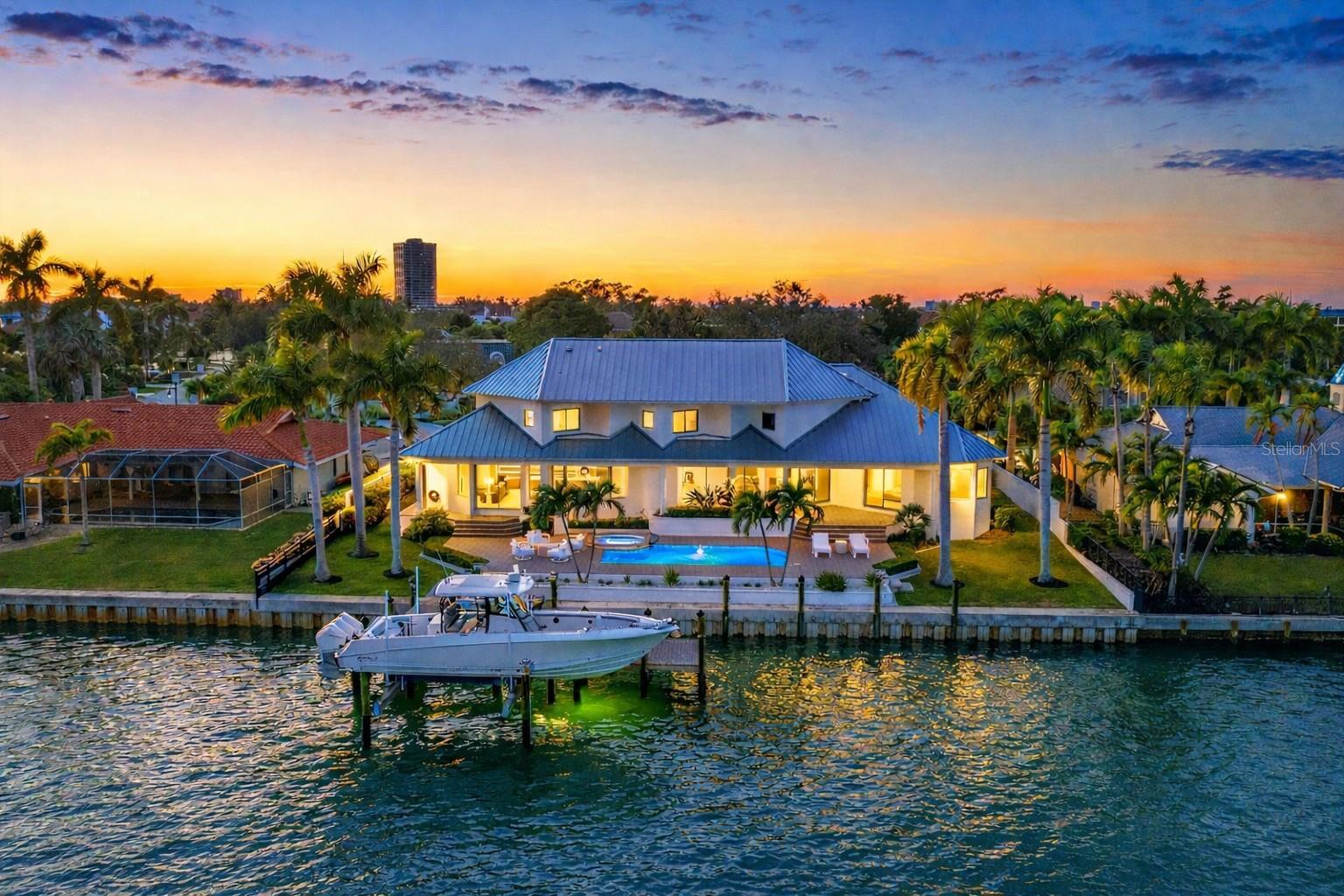 An exceptional opportunity on coveted Robin Drive in Bird Key, this fully reimagined bayfront home captures Sarasota’s waterfront lifestyle at its finest. Recently transformed through a meticulous, top-tier renovation, the residence showcases impeccable craftsmanship, elevated finishes, and a seamless blend of sophistication and comfort—where every detail and major system has been thoughtfully curated for effortless, modern coastal living. Elevated above the floodplain with a ground level over 10 feet, sweeping panoramic views span Sarasota Bay, the downtown skyline, and the iconic Ringling Bridge—creating a breathtaking backdrop from sunrise to sunset, with city lights shimmering across the water in the evening. Inside, more than 4,000 square feet of light-filled living space unfolds across two thoughtfully designed levels. Soaring ceilings up to 14 feet and expansive walls of glass bathe the interiors with natural light while framing unobstructed bay views throughout. The main living areas flow seamlessly from the inviting sitting room with a statement fireplace to the dining area and custom-designed kitchen, opening to the family room with a built-in bar—a wonderful gathering area to enjoy the gorgeous backdrop of the bay and downtown lights. The kitchen is anchored by a striking waterfall island and features designer-appointed custom cabinetry, premium Sub-Zero, Wolf, Bosch, and Miele appliances, and refined integrated details throughout. A fully equipped back kitchen and pantry, complete with an additional sink, appliances, and generous prep space, enhances functionality while maintaining a clean, polished aesthetic. The primary suite, privately positioned on the main level, offers direct access to the pool, dual walk-in closets, and a spa-inspired bath with a soaking tub, dual vanities, and elegant finishes. A dedicated office and two powder baths complete the main level. Upstairs, two en-suite bedrooms with bay views, a versatile bonus room, and an additional office space provide comfortable accommodations for family and guests. Outdoor living is equally compelling, featuring an expansive paver terrace, heated pool and spa, and unobstructed views of Sarasota Bay, downtown, and the Ringling Bridge—creating a serene waterfront retreat designed for everyday enjoyment. Set on protected waters, the property offers 120 feet of deep-water frontage along Bird Key’s Pompano Pass, with direct access to Sarasota Bay, Big Pass, and the Gulf. A newly constructed seawall and Trex dock feature fish and dock lighting, a 24,000-pound boat lift, and dedicated kayak and jet ski lifts—perfectly suited for an exceptional boating lifestyle. Additional highlights include a circular driveway, three-car garage with Tesla charger, and irrigation well. Bird Key offers an exceptional coastal lifestyle in one of Sarasota’s most coveted neighborhoods, just moments from downtown’s restaurants, shopping, and cultural venues, as well as the boutiques and dining of St. Armands Circle and the shoreline of Lido Beach. The Bird Key Yacht Club is currently undergoing a full redevelopment and is expected to reopen as a premier destination for boating, tennis, dining, and an active social scene.