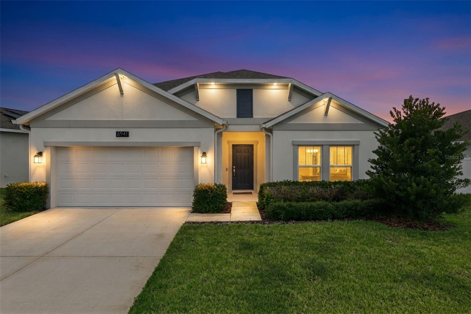 Are you thinking about buying or building a new home, but are unsure if you want to wait for the tedious process of permitting, builder delays and the multitude of unknowns?  If you answered yes, then why not consider a home that is only "3 years young" such as 6941 Dilly Lakes Ave.  Tucked away in Lake County, although only 10 minutes from the Florida Turnpike, Trinity Lakes is setting the bar for one of the most desirable communities to be in, and is well known for its resort-style amenities and low HOA.  Once across the threshold into the foyer, you can immediately begin to appreciate the three-way split floor plan; with two generously sized bedrooms are off to the right; serviced by a well updated bathroom in between, and a third bedroom conveniently located on the far right of the home, which makes an ideal space for a home office.  Tile flooring leads you down the hallway, into what is unequivocally the place where you will spend the most time; in the kitchen and family room, and this area does not disappoint!  These sellers have already added a custom feature wall that includes a two-sided fireplace, built-in shelving and lighting, all set with custom stonework.  Will your guests be impressed, you sure bet they will be!  If you have been the go-to home for hosting birthday's, holiday gatherings and family functions, you will now be the envy of your group, and it will inspire your friends to step up their home-design game even more.  Quartz countertops set the kitchen backdrop and provide ample prep space as far as the eye can see, with an updated light grey subway tile as the backsplash.  Your primary suite is perfectly positioned in the rear of the home and away from the other bedrooms for added privacy. It offers a feature wall of its own and a two-sided fireplace, setting the scene for a very comfortable and relaxing way to unwind. A well-updated en-suite bathroom with dual sinks, quartz counters, and a colossal walk-in closet (large enough to be a small office) complements this space.  Trinity Lakes is only minutes from some great destinations like Lakeridge Winery, Lake David Park, growing Downtown Clermont, Lake Catherine & much more.  NO REAR NEIGHBORS | WHOLE HOME WATER SOFTENER | LOW HOA | FULLY FENCED IN | GUTTERS ALREADY INSTALLED | > Don't you deserve to walk into a home like this everyday?