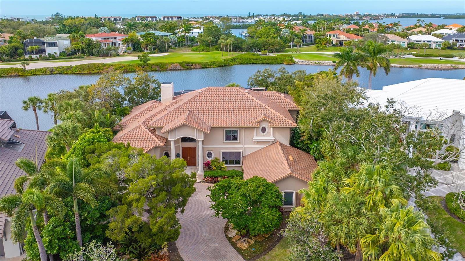Lakeside luxury living awaits in this grand and gracious residence with 4BRs/4BAs plus 2 half baths nestled within the prestigious Sabal Cove community behind the gates of the Longboat Key Club. As you approach, manicured landscaping invites you to the front entryway, where magnificent mahogany double doors open to reveal a foyer and dramatic 22’ ceilings and walls of glass. These expansive sliders showcase the serene waters of the heated pool and spa as well as the lake, with the golf course in the distance, providing tranquil vistas against the backdrop of striking sunset skies. The combination living and dining room area exudes warmth, centered around a fireplace that adds a touch of elegance to the space. The first-floor master bedroom boasts 14’ ceilings and offers sweeping views of the lake and pool. French doors open to the pool area, creating a seamless indoor-outdoor experience. The primary bath features include dual vanities, a makeup counter, etched glass and a beautifully designed walk-in shower with aquarium glass overlooking a private walled-in garden. For those who value a private study area, the first-floor library, with built-in floor-to-ceiling bookcases, provides a perfect retreat. The kitchen, a haven for gourmet gatherings, offers granite counters, a center island, gas cooktop, wall oven with a warming drawer and a separate wet bar. Double sinks and ample storage ensure that every culinary need is met, while the breakfast room overlooks the pool and family room. As you ascend to the 2nd floor, 3BRs with en-suite bathrooms await, with a exercise area and door opening to a balcony overlooking the pool and the serene lake beyond. Additional features include an alarm system, a brand-new roof in 2023, central vac, recessed lighting and an oversized 2-car side garage. As a resident, you'll enjoy all the privileges of the exclusive Bay Isles Beach Club. Longboat Key Golf & Tennis Country Club membership and Harbourside Moorings deepwater slips are available.