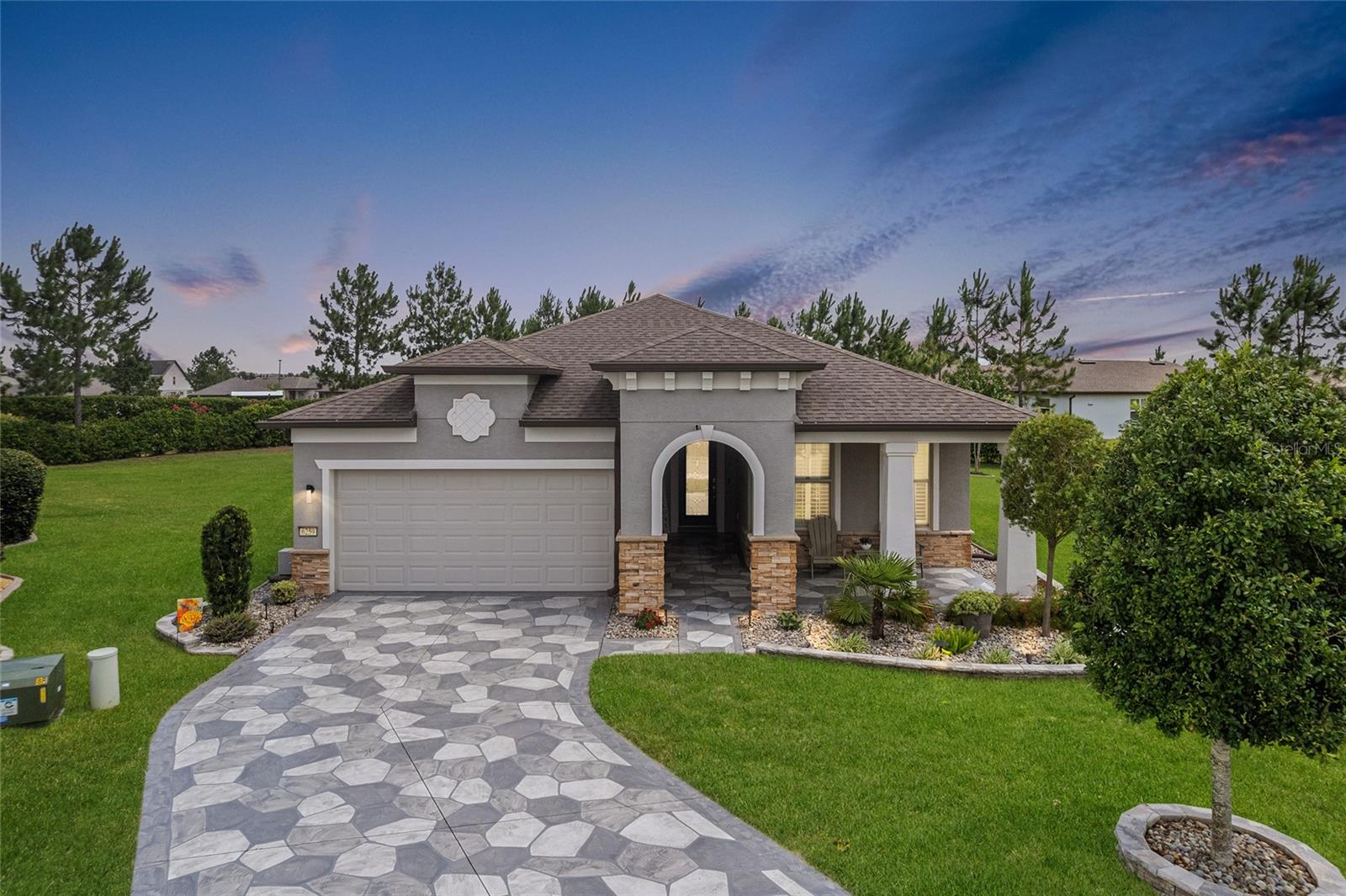 Impeccable details shine throughout this gorgeous Summerwood model, set on a large picturesque lot within the gated 55+ Stone Creek Golf Course Community. Immaculately maintained professional landscaping, along with a custom flagstone driveway and walkway, create a warm welcome to this stunning cul-de-sac residence. A spacious front porch offers a peaceful place to unwind, while the custom glass-inset front door sets the tone for the relaxed elegance found inside. This versatile and open floor plan is enhanced by designer-styled upgrades and touches throughout, featuring beautiful luxury vinyl plank floors, elegant crown molding, recessed LED downlighting, 8’ interior doors, and versatile spaces perfect for entertaining with family and friends. The top-tier chef’s kitchen is beautifully appointed with stainless steel appliances, a stainless range hood, detailed tile backsplash, granite countertops, and a large walk-in pantry. A generous center island with pendant lighting provides flexible dining space and overlooks the gathering room. Expansive glass sliders in the gathering room create a seamless connection to the outdoor living areas, offering tranquil views and effortless indoor-outdoor flow. Enjoy unwinding on the covered lanai, which opens to a large, expanded birdcage patio with flagstone flooring and generous space for entertaining. The outdoor paver-lined seating area overlooks professionally landscaped, lighted backyard views, creating a warm, inviting setting for evening gatherings and weekend barbecues. The owner’s suite unfolds as a serene, spacious retreat highlighted by a tray ceiling and a picture window dressed in Plantation shutters overlooking peaceful nature views. The expanded walk-in closet with custom built-ins and the spa-inspired bath, complete with a Roman-style walk-in shower, transom window, private water closet, and a double-sink vanity, enhance the sense of effortless comfort. Both bedrooms in the home have been recently updated with warranty-protected Berber carpet, and the guest bath includes a tile-lined tub/shower combination. The extended two-car garage is outfitted with overhead storage and durable epoxy flooring and offers space for a workshop or golf cart, while the interior laundry room offers added convenience with storage cabinetry and a laundry tub. Embrace the exceptional lifestyle of this vibrant community, featuring a 24/7 staffed gated entrance for security and peace of mind. Luxury-inspired amenities include heated pools, a state-of-the-art fitness center, a spa, and relaxing hot tubs and saunas. Stay active with pickleball, bocce, tennis, and a softball field, while a dedicated lifestyle staff curates entertainment, activities, and special events to foster connections. This master-planned community also offers a golf course, pro shop, and inviting on-site restaurant, creating effortless opportunities to relax, connect, and enjoy the Florida lifestyle. Make your move today and experience resort-style living at its finest.