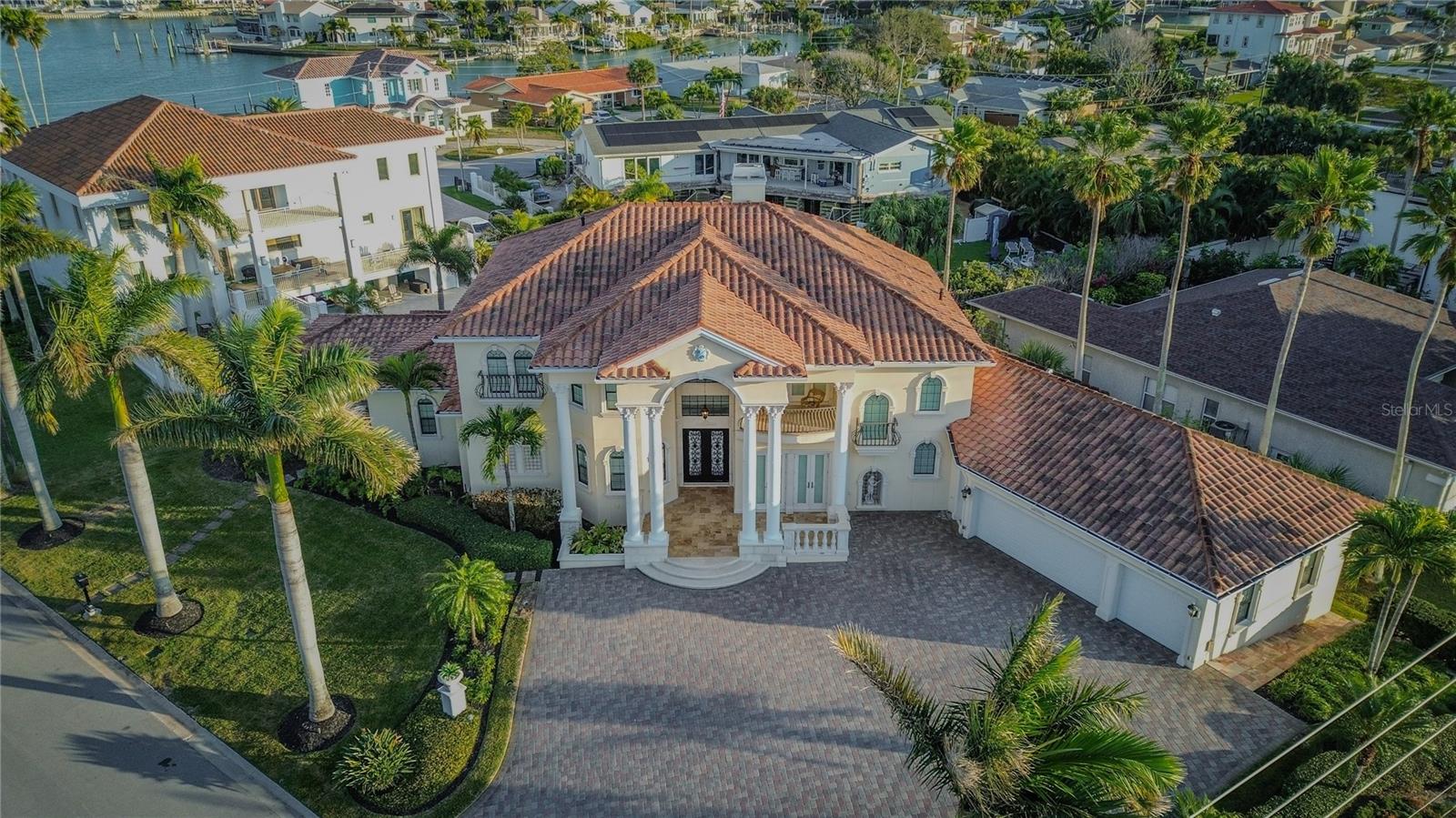 Virtually Staged. Significant price adjustment presents a compelling opportunity to own a luxury coastal home in Belleair Beach. One of the lowest flood insurance policies on the barrier islands, assumable at just under $1,800 annually. Elevated 5-bedroom residence located directly across from the Gulf of Mexico featuring rare dual water views of the Gulf and Intracoastal Waterway. Built above the flood plain in AE zone with hurricane-impact windows and doors, wind-mitigation-qualified tile roof, reinforced garage door, and whole-house Generac gas generator powering essential systems including HVAC, appliances, and lighting. Property performed as designed during recent storms, offering durability and peace of mind. Interior features include imported Italian marble flooring, custom ironwork, hand-painted tile murals, and a statement crystal chandelier. Spacious floor plan with five bedrooms plus executive office. Wraparound balconies span the second level with Gulf and Intracoastal views from nearly every room. Outdoor living includes private pool and spa with smart home technology controlling security, lighting, irrigation, and pool systems remotely. Conveniently located near Clearwater Beach, Dunedin, Tampa International Airport, and Downtown Tampa. Now offered at $3.05M, delivering strong value for a luxury waterfront lifestyle in Belleair Beach.  Professionally designed concept renderings have been included to illustrate a refined, modern coastal aesthetic, offering buyers a clear vision of how the home can be elevated with thoughtful updates. The property’s existing architecture and layout provide an exceptional foundation, allowing for meaningful transformation without the need for a full-scale renovation. Opportunities exist to enhance finishes, lighting, and overall design while maintaining the home’s character and structural integrity. For buyers interested in customizing the space, design consultation and renovation guidance are available.