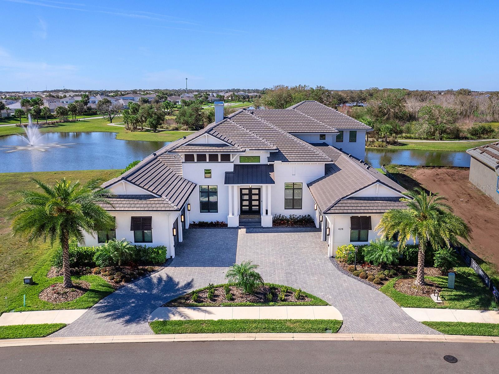 Located within the highly sought-after Star Farms at Lakewood Ranch, 4218 Butte Trail presents a rare opportunity to own a fully customized 2024 AR Homes by Arthur Rutenberg luxury estate showcasing panoramic lake, preserve, and sunset views. Offering approximately 6,488 square feet under air, this exceptional Lakewood Ranch residence features 4 bedrooms, 5 full baths, 2 half baths, a private office, gym with sauna, bonus room, wine room, and resort-style outdoor living spaces, delivering an unparalleled blend of luxury, comfort, and functionality. A grand entry framed by custom iron double doors and soaring transom windows opens to a light-filled interior where elevated design meets everyday livability. The expansive great room features a dramatic double-tray ceiling, contemporary media wall with linear fireplace, and walls of sliding glass doors that seamlessly connect indoor and outdoor living while maximizing the home's stunning waterfront setting. Designed for culinary enthusiasts and entertainers alike, the chef's kitchen serves as the centerpiece of the home, appointed with Sub-Zero refrigeration, Wolf double wall ovens, Wolf induction cooktop, Wolf microwave, Cove dishwasher, KitchenCraft cabinetry, an oversized center island, custom walk-in pantry, secondary café refrigerator, and reverse osmosis water system. Adjacent gathering spaces include a breakfast nook with zero-corner sliders, a formal dining room, butler's pantry with wine cooler, and a glass-enclosed wine room. The primary suite offers a private retreat overlooking the water, complete with custom walk-in closets, one featuring a center island, and a spa-inspired bath with a Kallista soaking tub, oversized steam shower, rainfall feature, dual vanities, makeup station, and private water closet. Upstairs, two guest suites with en-suite baths accompany a spacious bonus room featuring a wet bar, refrigerated drawers, and covered terrace overlooking the lake and preserve, creating an ideal setting for guests, multigenerational living, or entertaining. Outdoor living is designed to rival a private resort, highlighted by a screened lanai with tongue-and-groove ceilings, outdoor linear fireplace, expansive seating and dining areas, swim-up counter, and a fully equipped outdoor kitchen with a Wolf grill, sink, and refrigerator. The infinity-edge pool and spa overlook tranquil water and preserve views, creating an exceptional backdrop for both relaxation and entertaining. Additional features include a whole-home generator, whole-home water filtration and conditioning system, Hunter Douglas remote shades, plantation shutters, security cameras, tankless water heater, abundant storage, epoxy-finished garages, and wiring for four EV charging stations. Residents of Star Farms Lakewood Ranch enjoy access to one of the area's most impressive collections of resort-style amenities, including multiple pools, fitness centers, pickleball and tennis courts, dog parks, recreational facilities, and scenic walking trails. Conveniently located near Lakewood Ranch Main Street, Waterside Place, Sarasota, Bradenton, championship golf courses, top-rated schools, premier healthcare providers, shopping, dining, and Florida's world-renowned Gulf Coast beaches, this extraordinary residence offers the luxury lifestyle that has made Lakewood Ranch one of the nation's most desirable master-planned communities.