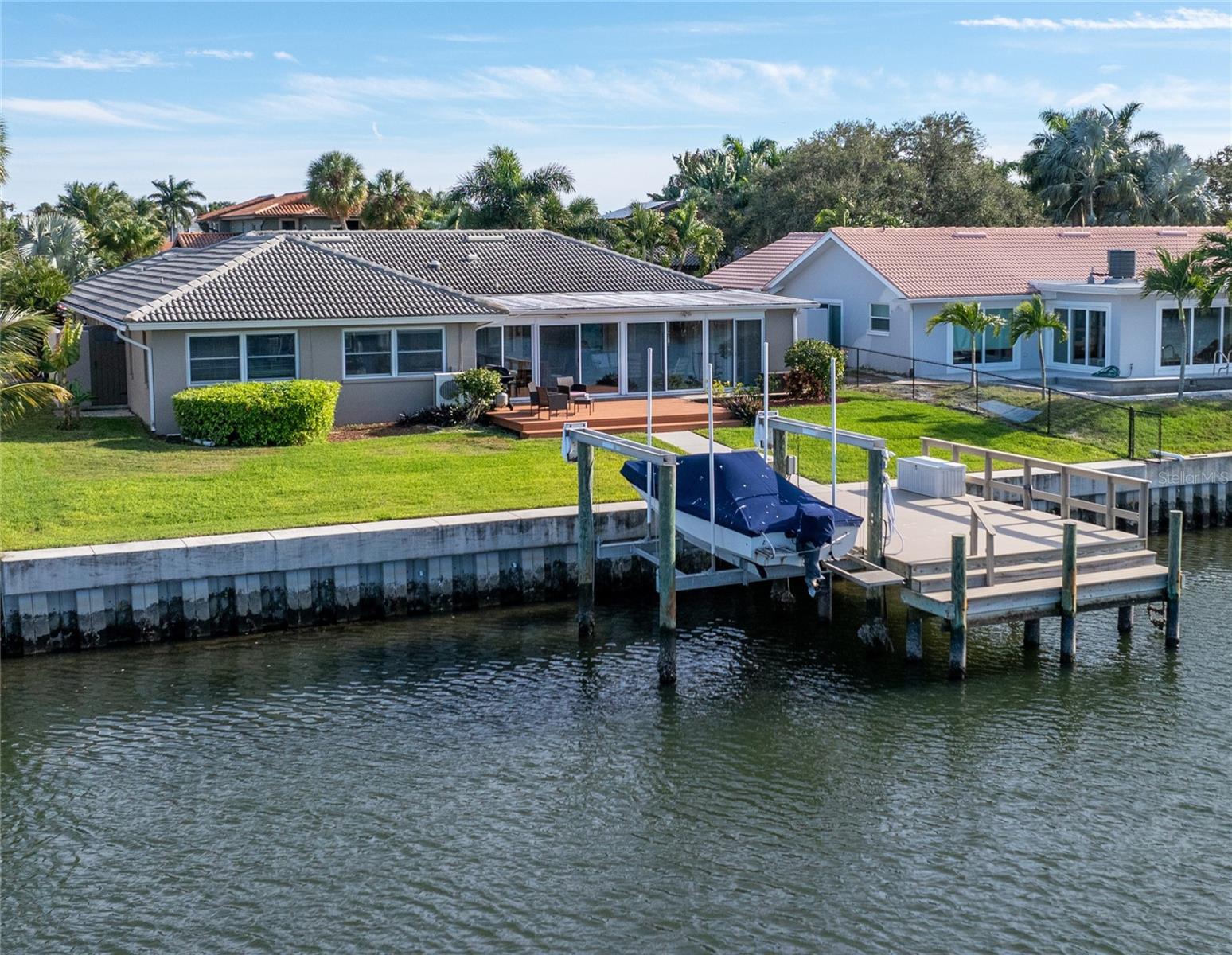 Welcome to Venetian Isles, enjoy this well maintained home with many features and upgrades including Simonton HURRICANE RATED WINDOWS throughout the home. An exceptional floorplan for today's lifestyle, this 4 bedroom home offers an expanded floorplan creating large living areas to enjoy gatherings with family and friends. The oversized 1/4 acre lot allows plenty of room to add a pool and maintain the green space. Newer composite dock, pilings and seawall with expanded cap alleviate your maintenance worries. An oversized paver driveway at the front of the home leads to a private courtyard entry where Florida tropical native plants invite you to the double door entry and foyer of the home. Formal living and dining areas flow seamlessly into the informal living space that overlooks the waterfront. A 16' x 32' Florida room takes full advantage of the water views and connects the family room, dining and kitchen spaces creating the perfect entertainment space. The kitchen has been remodeled and expanded to create additional storage and a built-in breakfast nook. Solid hickory cabinetry with many storage features are throughout, including a closet pantry. Stainless steel appliances and warm granite counters afford a cozy appeal and the pass thru window, bar counter keep the chef in your family at the center of the action. The main bedroom suite has views of the water, a walk-in closet and bath with double vanity and glass enclosed shower. Sliding doors open to a private atrium allowing lots of natural light into the space. The 4th bedroom is perfect for a guest room or office. On the opposite side of the home are two large guest bedrooms and a hall bath with double vanity and tub shower. Hard surface flooring throughout the home including laminate and porcelain tile. Indoor laundry room with storage connects to the attached two car garage. Outdoors large sliding doors open to an oversized deck and spacious backyard where a new composite dock 16'x26', sidewalk & pilings were recently replaced. Water, electric and fish cleaning station along with a deck box provide all the perks for the fisherman. The boat lift accommodates 9,000lbs. Tile roof replaced 2000, Florida room addition completed 2008, AC 2013 w/ warranty. Come enjoy the Florida waterfront lifestyle in this beautiful community - just minutes from downtown St Pete, highly sought after and favored for boaters due to it's deep water canals designed for easy access to Tampa Bay's beautiful waterways. Known for its beautifully manicured tropical landscaping, water views, friendly community and close proximity to downtown St. Petersburg this home embodies it all!