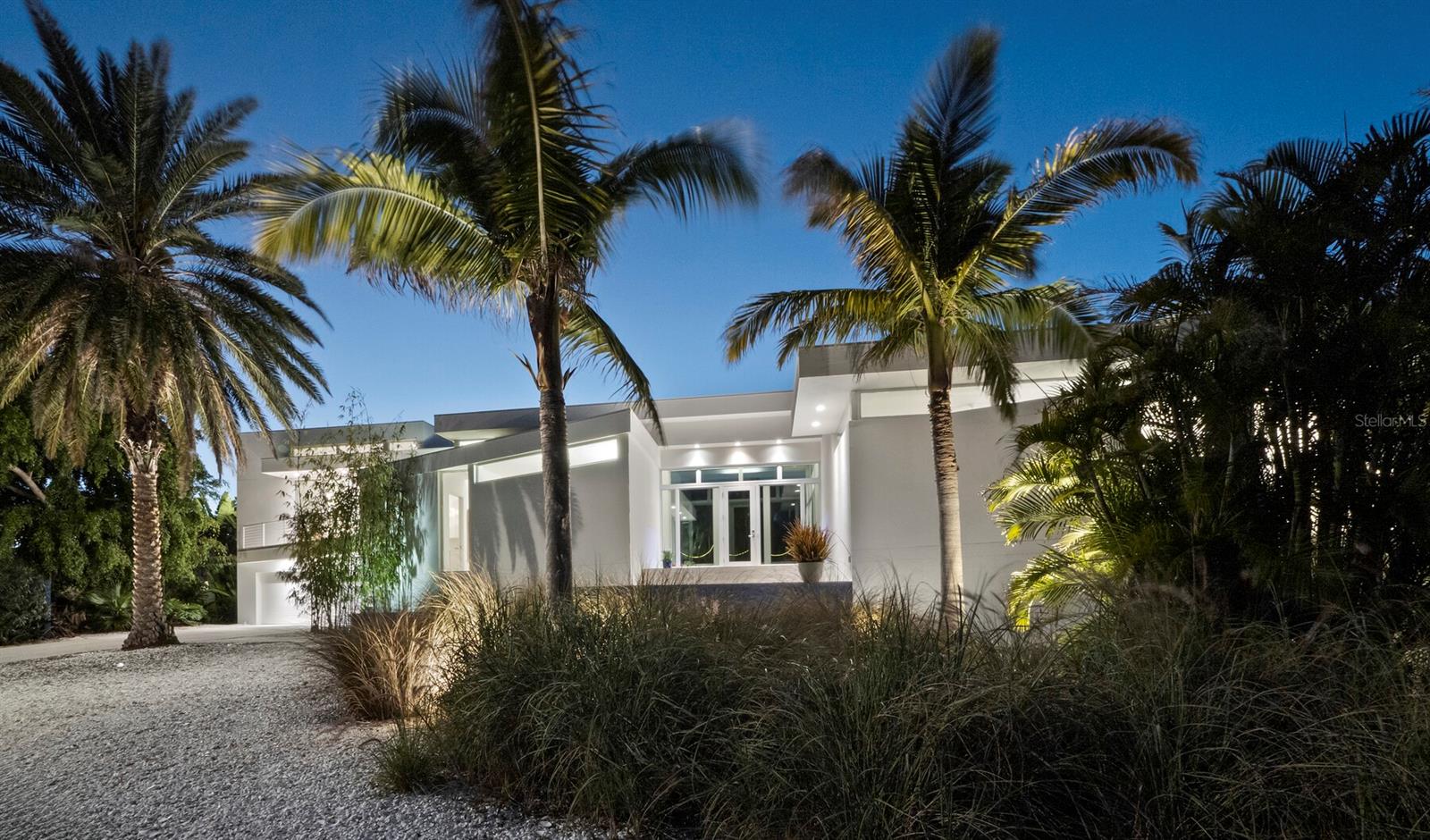 An icon of modern design in the style of the world-renowned Sarasota School of Architecture, 1235 Center Place combines award-winning pedigree with exceptional luxury in a setting that is as coveted for its natural beauty and access to amenities as for its storied mid-century and modern estates. Known as the Light Box House for its distinctive angles and use of glass walls to showcase courtyard and exterior views, this home was custom built in 2012 by the current owners to foster both idyllic privacy and elevated hospitality. The home and architect Jonathan Parks have been widely celebrated for its design, winning the AIA Tampa Bay Merit Award for Architecture and the Grand Aurora Award for a custom home, with features in the Herald-Tribune’s Style Magazine, Sarasota Observer, and HomeDSGN magazine. Occupying the corner lot of Westway and Center and two doors away from the famed Umbrella House, the home is thoughtfully oriented around a central pool that serves as a focal point for both reflection and recreation. Stretching between north and south wings that gently delineate spaces for private retreat and open entertaining, 3,700 A/C square feet encompass three bedrooms with three and a half bathrooms, an office, an open concept gourmet kitchen and adjacent dining and living space, all purposefully positioned to capture optimal light and accentuate the interplay of built features with the tropical landscape. An elegant contrast to the brilliant sky and foliage outside, the interior is a refined gallery that meticulously balances walls of glass with solid surfaces for display and function, from art-hung walls to Caesarstone countertops. While complementing the mid-century style of surrounding homes, contemporary construction here offers the significant advantages of elevation for flood consideration, high-efficiency impact rated materials, and modern integrations including heated primary bathroom floor, motorized window coverings, Generac generator, LED landscape lighting, and more. Recent upgrades include two Carrier Infinity HVAC systems installed in 2025 and 2024. Lido Shores is coveted for its concentration of mid-century, modern, and post-modern homes, with masterpieces by Paul Rudolph, Carl Abbott, Don Chapell, and others renowned for their architectural influence. Enhancing its island luxury, this residence enjoys the ultimate and rare privilege of deeded access to a private white sand beach and covered pavilion exclusive to Lido Shores property owners. Serene and private but within minutes of St. Armands Circle and Downtown, this special island enclave offers immediate access to the tropical waters of Sarasota Bay and the Gulf and innumerable cultural amenities that include fine and performing arts, dining, and shopping.