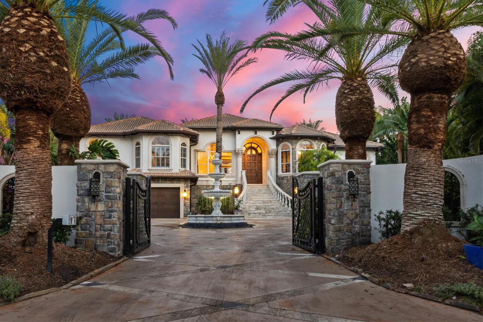 Welcome to 1384 Harbor Drive, an exquisite waterfront residence nestled in the prestigious Harbor Acres neighborhood located just minutes from Downtown Sarasota. Situated on an impressive 150 feet of water frontage, this residence caters to the boating enthusiast. A custom oversized teak dock, equipped with two lifts and ample space for additional boats or personal watercraft on a protected basin, is truly unique.  Updated from 2006 to 2008, the home reflects a commitment to quality and sophistication. As you approach, automatic gates welcome you into a tranquil courtyard featuring an impressive marble water fountain, surrounded by impeccably landscaped gardens. The outdoor areas are designed for both intimate gatherings and grand events, offering views of the sunset over the peaceful bay waters. The expansive terrace, accessible from the family and living rooms, comes complete with an outdoor fireplace and grilling area, creating the perfect setting for entertaining. The Mediterranean-influenced backyard gardens complement an infinity-edge pool, handset with thousands of mosaic tiles, providing a luxurious retreat for relaxation and recreation. Featuring 4 bedrooms, 5 full bathrooms, and 1 half bathroom, spread across 4,027 square feet this home showcases meticulous attention to detail and superior craftsmanship. Cozy formal and informal living spaces create plenty of room for family and guests to unwind after a day on the water, at the beach or at one of Sarasota’s nearby cultural events.  The kitchen flows seamlessly into the family room and features white cabinetry, professional stainless-steel appliances, an island with bar seating, and a breakfast area with a large picture window showcasing the water views. The primary suite boasts two full bathrooms each with a large walk-in closet. Additional highlights include an elevator, an enormous walk-in wine cellar, a 2,700 ft bonus area, and a six-car custom garage complete with a workroom. With its amazing waterfront location and impeccable design, this residence offers an unparalleled lifestyle. Enjoy all that this location has to offer within minutes to Southside School, Southside Village, Sarasota Memorial Hospital, Siesta Key, and Downtown Sarasota.