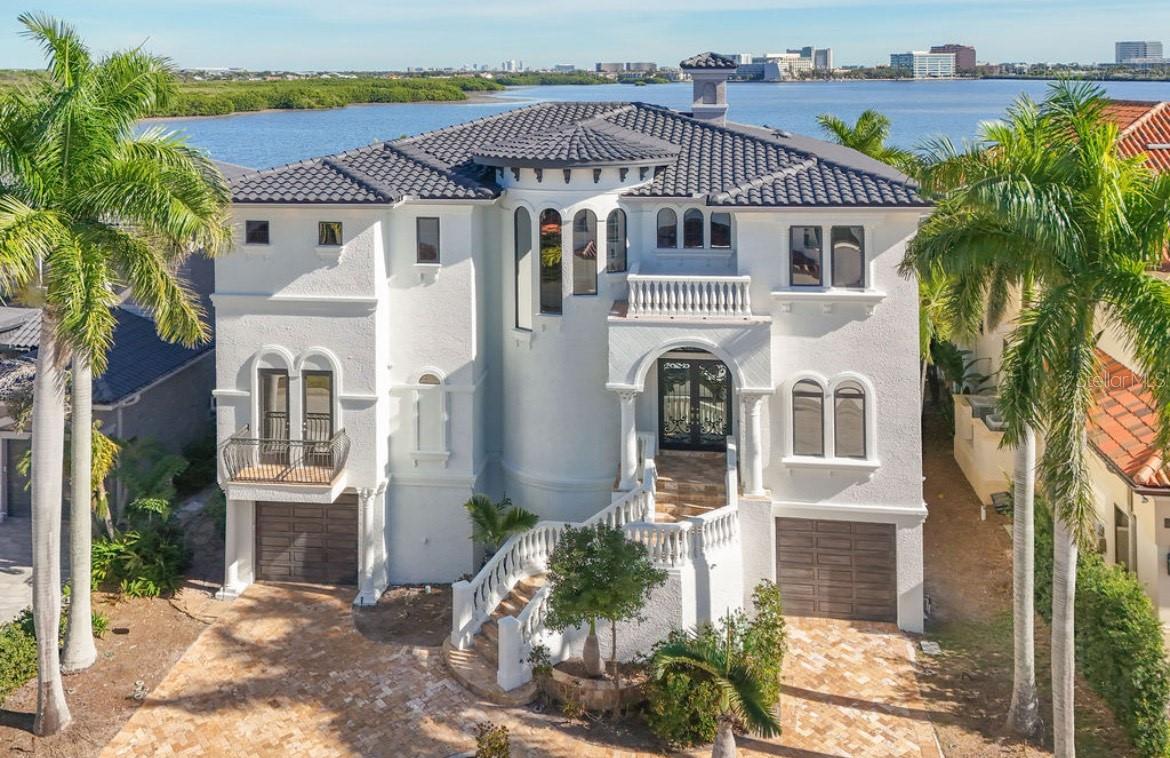 One or more photo(s) has been virtually staged. Experience this sleek, modernized Mediterranean masterpiece in an elite Alvarez community, featuring Tampa Bays most expansive waterfront. Brand new tile roof, vibrant fresh paint inside and out. Glide up the chandelier lit elevator to break taking bay views on entry level. Main Floor dazzles with a gourmet kitchen, Wolf Gas Stove, Sub Zero Fridge, massive island, beige cabinetry, pristine white granite; cozy fireplace living room; elegant dining room; travertine floors flowing to a grand balcony with full outdoor kitchen. The upper level has rich cherry hardwoods; luxurious primary suite, guest bedroom; epic 10 speaker theater with starry ceiling and power recliners; and a terrace showcasing endless water vistas. The lower level thrills with a wine room, entertainment hub, private mother in law suite, sparkling pool/spa with a cascading waterfall and fountain, the second outdoor kitchen is on the expansive wood deck. There is also a versatile space for a 5th bedroom or office. Comfortably take the elevator to each floor for ultimate convenience. The whole home has sonos audio perfect for entertaining. The Ultimate dock has a 16k lb boat lift, dual sea-doo lift; stunning pergola with glowing bar commanding a full bay panoramic view. This amazing property is close to the Tampa International Airport, Downtown Tampa, St Petersburg, the world class Gulf beaches, Michelin star restaurants and so much more. This home is the embodiment of waterfront luxury! (Renovation photos for Inspiration only)