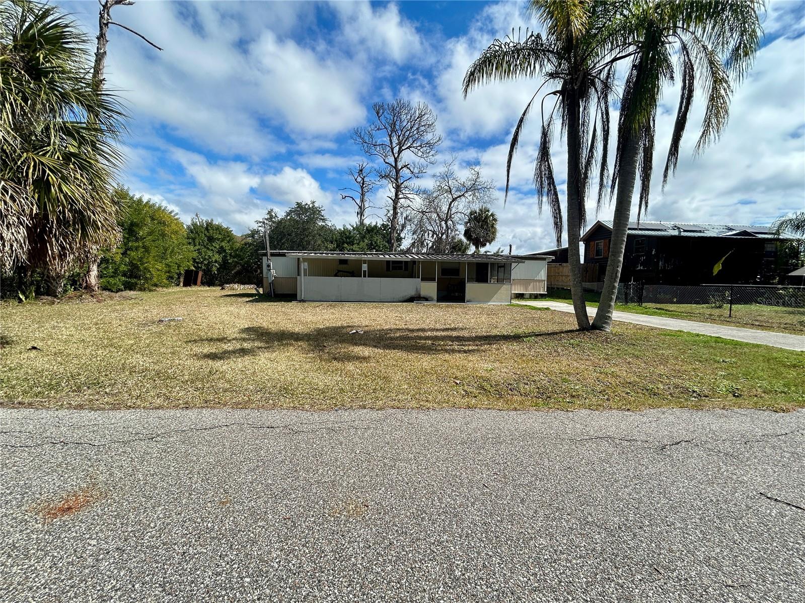 Build your vision in the heart of New Port Richey with this cleared 0.15-acre homesite offering 66 feet of paved road frontage. The lot is mostly cleared and dotted with a few ornamental palm trees, creating an attractive starting point for your future build.
An existing manufactured home and detached storage unit are on site and will need to be demolished, creating a blank canvas for a new elevated residence built to current code requirements. A septic tank is already in place, and water service is provided by a utility company — no well required. Electricity is also available on site, potentially reducing initial development costs. Buyers should verify utility connection status and septic condition during their due diligence. Impact fee payment status should be confirmed directly with Pasco County, including possible prior credits and current fees for new elevated construction.
There is an expired demolition permit on record that will be the responsibility of the new owner to resolve. For safety reasons, there is no access to the existing structures. Enjoy the freedom of no HOA and no lot rent — just true land ownership and full control over your plans. Bring your builder and your ideas, and transform this property into your own elevated oasis.
