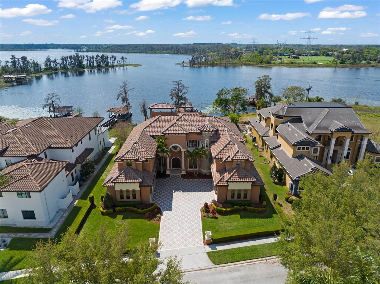 Welcome to a residence where the essence of lakeside opulence meets the prestige of Bay Hill's championship golf course, creating a haven of unparalleled sophistication and relaxation. Lying within the guard-gated community of Emerson Pointe, this is more than just a home - it's an exquisite retreat where luxury meets lifestyle in perfect harmony. The epitome of charm and elegance embodies this custom lakefront home, nestled along Lake Chase, one of the famed Windermere Chain of Lakes. With close to 100 feet of lake frontage, this exquisite property offers a lifestyle of unparalleled luxury. Here's your exclusive chance to immerse yourself in the coveted Florida Chain of Lakes lifestyle where boat life becomes an integral part of daily living. Picture yourself spending leisurely days cruising along the tranquil waters fishing or simply soaking in the breathtaking scenery. Elevated on a little over 1-acre lot, the estate cascades down to the scenic waterfront, complete with a renewed dock built in 2025, covered/tiled boat lift, and double jet ski lift, inviting you to indulge in the ultimate lakeside living experience. Every corner of this home is meticulously designed for both comfort and sophistication. Enjoy 7 bedrooms, 7 full and 1 half baths, a home theater, a wine cellar, and an office. Step into the lavish embrace of a recreation sanctuary, a haven crafted for indulgence and leisure. The gourmet kitchen is a chef's dream featuring stainless steel appliances, a 48-inch refrigerator, 6-burner gas stove, pasta spigot, custom-made cabinetry, and beautifully crafted Giallo granite countertops all accentuated by wood beams overlooking picturesque views of the tranquil waters. The primary suite, complete with a gas fireplace, is a sanctuary of luxury and tranquility offering unparalleled vistas of the tranquil waters below. Overlook the Butler Chain from the second and third-story balconies which capture panoramic vistas of the nightly Disney fireworks that captivate the senses and soothe the soul. Recent upgrades include a $315,000 new roof and renovated balconies, ensuring both timeless elegance and structural integrity. Other amenities include: 24-Hour Guard, 6 garage stalls, onyx master bathroom countertops, central vac system, Tesla charging station, elevator, exterior travertine pavers, summer kitchen, and so much more. Whether unwinding with a cinematic masterpiece in the plush confines of the media room or engaging in lively gatherings with loved ones, every moment will be cherished. Additionally, indulge in the vibrant culinary scene just moments away at Restaurant Row, where a multitude of dining experiences await. Golf enthusiasts will appreciate the proximity to Bay Hill's Country Club, offering unparalleled opportunities to perfect their swing on pristine fairways . Here, luxury living seamlessly blends with the convenience of nearby amenities, ensuring a lifestyle of sophistication and leisure.