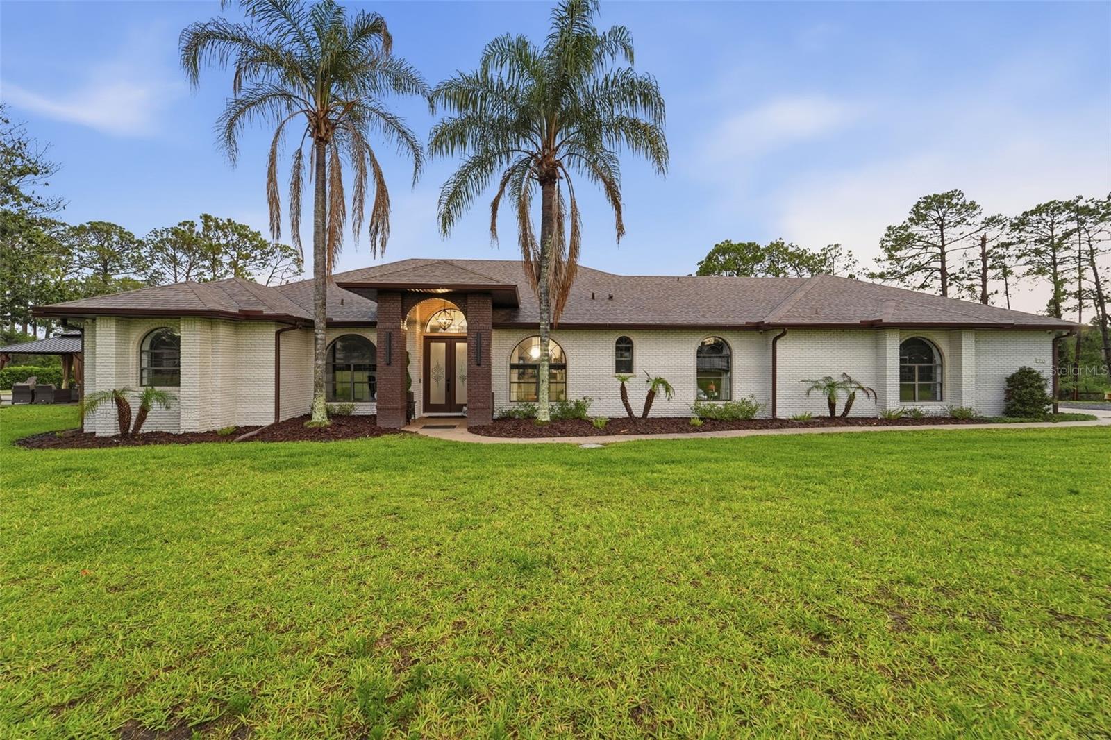 Rare opportunity to own a completely transformed, turnkey 5.2-acre agricultural lakefront estate on Lake Middlemass. Located in the heart of Seminole County with NO HOA, this highly desirable property sits directly across from Lake Sylvan and is zoned for the A-rated Wilson Elementary school (just a 2-minute drive away). Walking distance from Sylvan Lake Park, home to the Orlando Pride NWSL training grounds.Behind the secure, automated double-gate entry, the home offers a spacious 2,711 SQFT layout. No detail was spared in this top-to-bottom luxury renovation, offering absolute peace of mind with a whole-house plumbing re-pipe, seamless gutters, new interior/exterior paint, and energy-efficient LED lighting. Bring your largest toys. The oversized garage boasts ultra-high ceilings perfectly designed for boat parking.Roughly one acre of the main property is fully fenced, featuring a convenient gate that leads directly to your second vacant parcel. Because of the agricultural zoning, you have the rare freedom to build a massive workshop, a barn, a detached next-gen guest house, or an ultimate detached garage. Elite mechanical upgrades include newly installed FPUC natural gas lines, a gas tankless water heater, a premium water softener, and an Iron Boss water treatment system.Inside, brand-new luxury vinyl plank (LVP) flooring flows into a show-stopping chef's kitchen. This culinary masterpiece features luxury cabinets reaching the 10ft ceilings, premium waterfall-edge countertops, a massive island, and an elite appliance package with a gas cooktop, double oven, and drawer microwave. The open living space centers around a beautifully remodeled fireplace with a custom mantel. All three bathrooms have been completely reimagined, highlighted by a master retreat featuring a luxury standalone soaking tub, a custom rain-head shower, and a private 2–3 person sauna. The fully remodeled laundry room adds ultimate convenience with extra storage and versatile gas or electric dryer hookups.Step outside into your private backyard paradise. Extensive excavation has cleared over an acre of pristine lawn space, completed with fresh St. Augustine sod, professional landscaping, and a brand-new 10-zone irrigation system. Enjoy year-round outdoor living with a gas hot tub heater and a stunning outdoor gazebo set on a massive 25’x16’ concrete patio. Sports and entertainment enthusiasts will love the professional 30’x50’ concrete basketball half-court equipped with a MegaSlam XL Hoop. Storage is a breeze with an additional 10’x12’ concrete pad featuring a new Lifetime shed.This one-of-a-kind agricultural paradise perfectly blends high-end modern design, elite infrastructure, and endless possibilities. Schedule your private tour today!