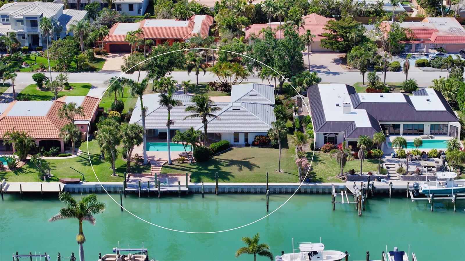 One or more photo(s) has been virtually staged. Perfectly positioned on deep canal waters just moments from Sarasota Bay, this Bird Key residence captures the essence of relaxed coastal living. Set on a generous lot and framed by tropical landscaping, this home blends privacy with proximity to Sarasota’s vibrant downtown and waterfront destinations. A circular brick-paver driveway leads to the welcoming front entry, while a brand-new roof (2024) offers peace of mind. Inside, more than 2,400 square feet of light-filled living space unfolds across an open, thoughtfully designed floorplan. Neutral oversized tile flooring flows throughout the main living areas, unifying the open-concept kitchen, family room, and dining spaces. The kitchen boasts granite countertops, sleek cabinetry, stainless steel appliances, a breakfast bar, and expansive counter space—ideal for both daily living and effortless entertaining. Walls of sliding glass doors extend the living area out to the screened lanai, where a covered lounge and pavered deck frame the sparkling pool. The residence features three spacious bedrooms, including a private primary suite with large walk-in closet and a en-suite bathroom. The home’s split-bedroom layout ensures comfortable accommodations for guests, while ample storage and a generous laundry area add everyday functionality. A newly rebuilt seawall (2022) and deep-water dock provide direct access to Sarasota Bay, making this a true boater’s retreat. Enjoy morning coffee or sunset cocktails with tranquil canal views just steps from your back door. Bird Key is one of Sarasota’s most sought-after neighborhoods, prized for its central location, manicured streets, and strong sense of community. Residents enjoy proximity to the Bird Key Yacht Club, with optional membership for boating, tennis, fitness, and dining. Just minutes away are the world-class shopping and dining of St. Armands Circle, pristine beaches of Lido and Longboat Key, and Sarasota’s thriving arts and cultural district.
This residence offers an opportunity to live on the water with generous indoor and outdoor spaces—perfect for savoring the Florida lifestyle in style and comfort.