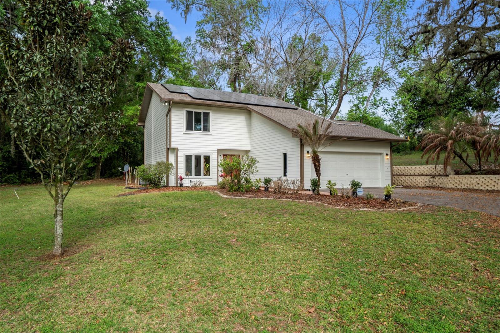 Discover your own slice of paradise on 5.66 acres of peaceful country living, just minutes from dining, shopping, and entertainment in Dade City and North Tampa. Surrounded by towering oaks and lush landscaping, this property has no HOA or CDD and can be subdivided for a family compound. Inside, large windows and gleaming bamboo floors welcome you into the living room, with a spacious Great Room at the back offering stunning views of Florida’s countryside. The gourmet kitchen features stainless steel appliances, newer cabinets, and granite countertops, while French doors off the dining area open to a screened porch overlooking your park-like setting. Upstairs, the 14x16 main bedroom boasts an ensuite bath, with two additional bedrooms sharing a second bathroom. Built with durable metal framing, this home offers energy savings with Paid Off solar panels (installed 2025), new windows (2025), a high-efficiency RUUD AC (2023), a 2016 water heater with updated elements, and a new roof (Feb 2023). The property includes a spacious two-car garage and an impressive 30x40 detached workshop with 15-foot ceilings, heavy-equipment capacity, RV storage, multiple 220-volt outlets, air lines, water access, a 14-foot roll-up door, and a heavy-duty car lift. A paved driveway completes the package—perfect for enjoying scenic walks, birdwatching, and the tranquility of country life with no neighbors in sight.