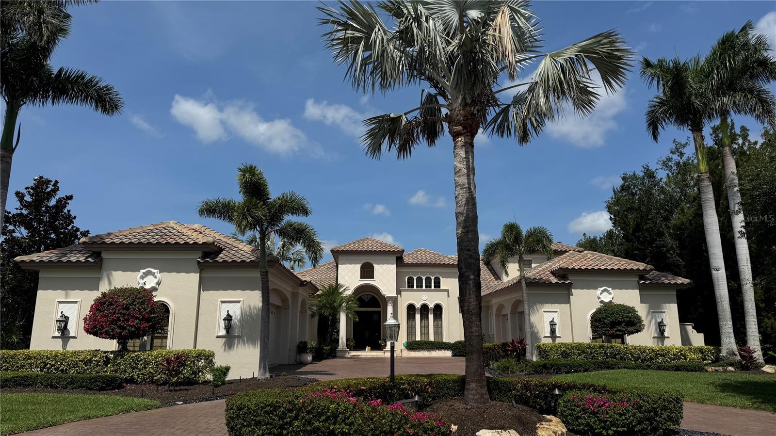 Exquisite Mediterranean Estate in Lakewood Ranch Country Club.  Nestled behind the gates of Lakewood Ranch Country Club, this magnificent Mediterranean-style estate offers a harmonious blend of luxury, comfort, and timeless elegance. Located in the exclusive Teal Creek neighborhood, the residence is surrounded by lush landscaping and serene golf course frontage, providing a tranquil retreat for discerning homeowners. As you approach the property, a circular paver driveway leads to an impressive façade adorned with arched double doors and wrought-iron accents. Inside, the grand living room welcomes you with soaring pecky cypress ceilings, travertine flooring, and a dual-sided fireplace, creating an inviting atmosphere for both relaxation and entertaining. The gourmet kitchen is a chef's dream, featuring high-end appliances, walk-in pantry, multiple workspaces, and ample storage. Rich textures and finishes invite guests to gather and enjoy culinary delights. Expansive glass sliders open to a stunning outdoor living area, where a paver lanai, updated summer kitchen, fireplace, and an expansive pool and spa await, all set against the backdrop of tranquil mature landscaping. The main-floor master suite is a sanctuary of luxury, showcasing hardwood floors and a spa-like bathroom. Two additional bedrooms are thoughtfully placed throughout the first floor, each boasting full en-suite bathrooms to ensure privacy and comfort for family and guests. Fourth bedroom is located on the second floor with easy access to the second floor lanai and bonus room. Situated on a generous half-acre lot, the property offers a perfect balance of indoor and outdoor living spaces. The five-car garage provides ample storage, while the meticulously maintained grounds reflect the home's commitment to quality and elegance. Live stress free with whole house generator and impact glass.  Located in the heart of Lakewood Ranch, residents enjoy access to top-rated schools, premier golf courses, and a vibrant community with a plethora of dining, shopping, and recreational options. This estate embodies the pinnacle of Florida luxury living, offering an unparalleled lifestyle in one of the state's most sought-after communities.