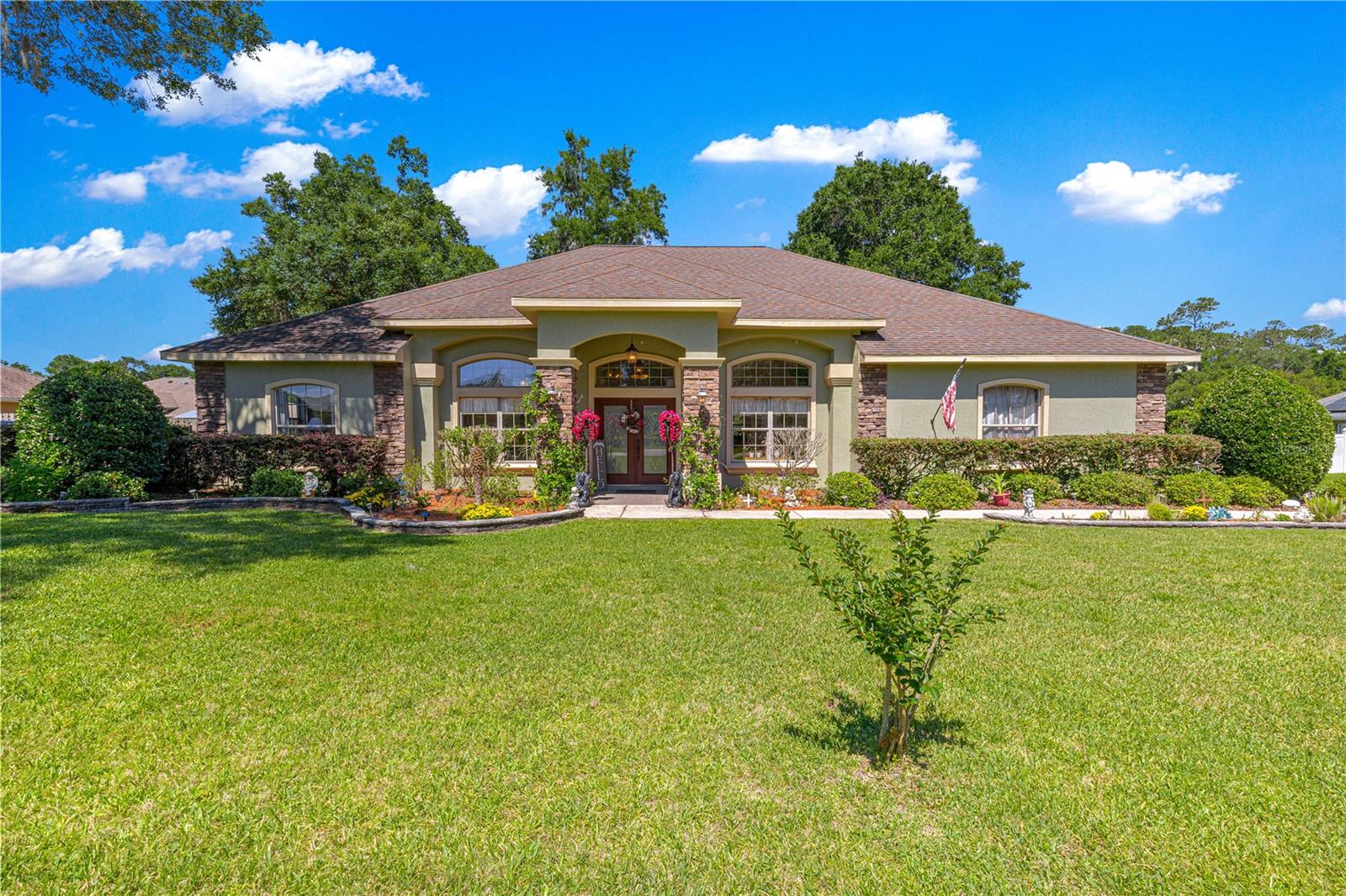 Beautifully crafted Huntington floor plan POOL HOME by A.L. Milton located in the family-friendly gated community of Cobblestone in
Belleview, Florida. This centrally located home offers exceptional curb appeal with a stacked-stone façade, double leaded glass entry doors, side-entry two-car garage, and extended driveway. Inside, you are welcomed by a large open foyer leading to a formal sitting room or flex space with double doors and crown molding. The formal dining room features double French doors, tray ceiling, crown molding, designer chandelier,and elegant finishes including 5-inch baseboards throughout. The spacious family room showcases cathedral ceilings, a natural stone gas fireplace, and custom built-in arched nooks with additional cabinetry. The open kitchen offers granite countertops, maple cabinetry, stainless steel appliances, double stainless sink, large pantry, breakfast nook with wainscoting, and a breakfast bar accented with stacked-stone detail. The indoor laundry room includes additional cabinetry, deep utility sink, and Samsung washer and dryer only
one-year-old. The large primary suite features crown molding, tray ceiling, private access to the Lanai and pool area, dual vanities, jetted garden tub, Roman shower with seating, and a spacious walk-in closet. Three additional bedrooms are generously sized with tile flooring and ceiling fans. Guest bathrooms feature cultured marble countertops, maple cabinetry, and tiled tub/shower surrounds. Outdoor living is designed for entertaining with a solar-heated chlorine pool featuring a waterfall, birdcage enclosure, spacious deck area, mature landscaping, and a fully equipped summer kitchen with propane grill and refrigerator. Additional features include a fully fenced backyard, whole-home wired sound system, King security system, and pull-down attic stairs in the garage. Residents of Cobblestone enjoy a gated community atmosphere with a neighborhood park featuring swings, picnic tables, benches, and green space for gathering and recreation for the entire family!
