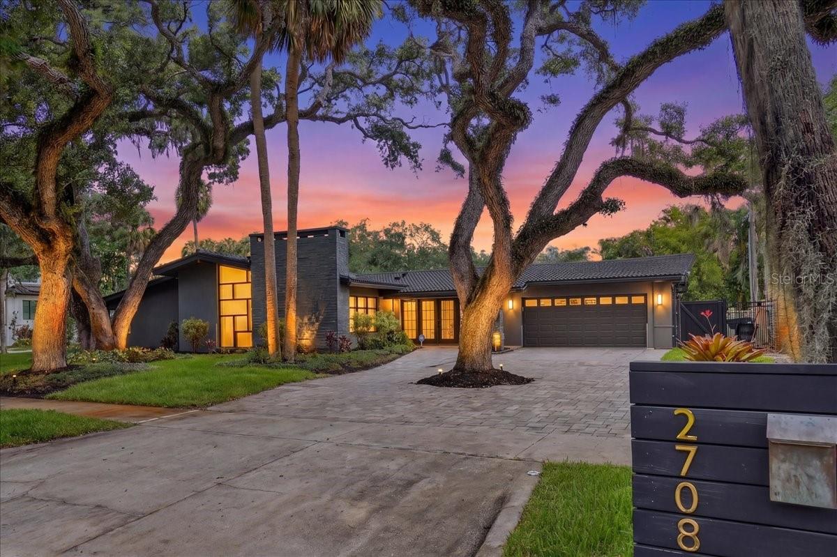 One or more photo(s) has been virtually staged. Positioned on an oversized corner lot in the heart of South Tampa, this exceptional mid-century modern residence masterfully blends iconic architectural design with elevated contemporary living. Originally built in 1957 and extensively renovated, the single-story home offers a rare combination of timeless character and modern functionality, within one of Tampa’s most sought-after neighborhoods and top-rated school districts.
Set on a more than 13,000 sq. ft lot and surrounded by mature landscaping, the property was thoughtfully designed for seamless indoor-outdoor living. Expansive entertaining spaces open effortlessly to a private backyard retreat featuring a sparkling pool and spa, screened pool enclosure, full pool bath, and a fully equipped outdoor kitchen complete with a Wolf grill, large sink, ice chest, and abundant storage. A dramatic natural gas fire feature and specialty landscape lighting create a striking ambiance after sunset. The home is wired with an indoor and outdoor sound system to enhance every entertaining experience.
Inside, clean architectural lines, soaring ceilings, and walls of glass fill the home with natural light and create an inviting atmosphere. The thoughtfully designed floor plan includes three spacious bedrooms, four-and-a-half bathrooms, and multiple living and gathering spaces curated for both everyday comfort and elevated entertaining.
A welcoming foyer immediately showcases the home’s distinctive character and provides access to the attached two-car garage and a conveniently located powder bath. The main living area features vaulted beam ceilings and a stunning floor-to-ceiling stone fireplace, anchoring the space with timeless mid-century appeal.
The chef’s kitchen is both functional and beautifully designed, offering dual islands, extensive prep space and storage, premium appliances, sleek oak cabinetry, a floating stainless steel hood, and a versatile breakfast bar that can also serve as a stylish dry bar for entertaining. Adjacent open dining and living spaces provide flexibility for hosting, relaxing, or game nights with family and friends.
Each bedroom is generously sized and includes a beautifully appointed ensuite bath with luxury finishes. The primary suite serves as a true private retreat, featuring direct access to the pool area, a spacious walk-in closet, and a spa-inspired bathroom complete with a wet room, hammered metal soaking tub, dual shower heads, steam plumbing, and a dual sink vanity. An adjoining flex space offers versatility for a sitting room, office, nursery, or fitness area.
The second bedroom is ideal for guests or family, while the third bedroom—currently utilized as a media room with a full bath—offers endless possibilities to fit the next owner’s lifestyle.
Additional upgrades and features include a new roof, pool equipment, security system, irrigation supplied by well water, and a professionally installed perimeter water barrier system for added peace of mind.
Perfectly positioned and directly across from a park, 2708 N. Dundee Street offers convenient access to Tampa’s premier dining, shopping, waterfront amenities, downtown Tampa, Tampa International Airport, and some of the area’s finest public and private schools.
This is a rare opportunity to own a fully renovated architectural residence on a substantial corner lot in the heart of South Tampa. This home captures the essence of Florida living at its finest.