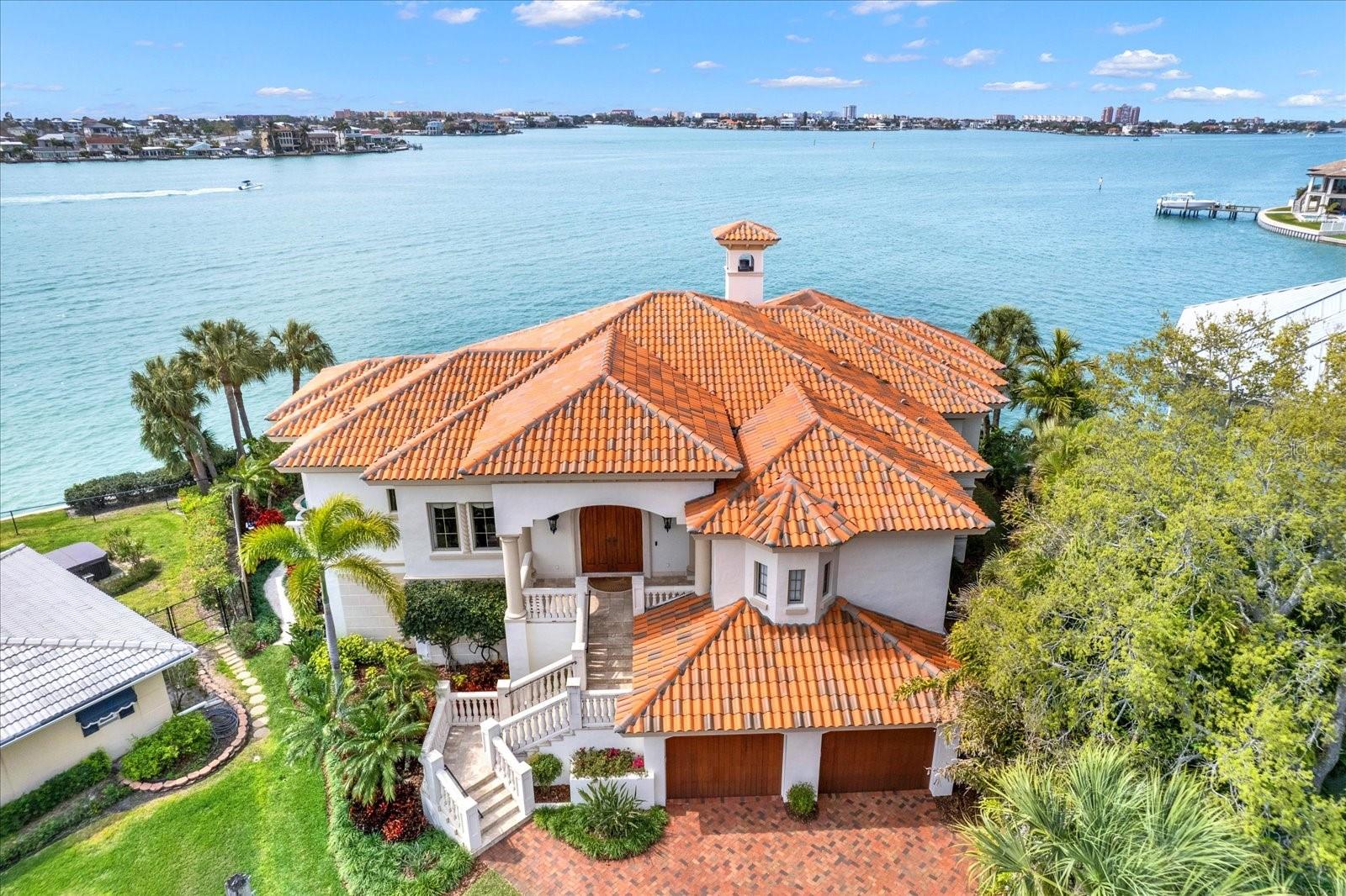 WELCOME TO THIS WATERFRONT MASTERPIECE IN THE PRESTIGIOUS OAKHURST SHORES NEIGHBORHOOD OF SEMINOLE! SITUATED ON A SPECTACULAR POINT LOT WITH 136 FEET OF BREATHTAKING DEEP-WATER FRONTAGE, THIS CUSTOM-BUILT 2009 ESTATE WAS METICULOUSLY DESIGNED FOR THE MOST DISCERNING BUYER, OFFERING AN ELEVATED COASTAL LIFESTYLE WITH UNRIVALED LUXURY AND SOPHISTICATION. Built with solid block construction from top to bottom with almost 8,000 Sq Ft of space under the roof, step inside and enjoy the expansive open-concept living spaces, soaring coffered ceilings, and panoramic water views from nearly every room. The living area boasts a custom wet bar and a 392 BOTTLE TEMPERATURE CONTROLLED WINE ROOM adjacent to the chef’s kitchen, while a natural gas fireplace, TV, and built-in gas grill on the covered balcony create the ultimate ambiance for grilling, lounging, and taking in unforgettable sunsets over the Intracoastal Waterway. The HOME THEATER (with soundproofing) offers an unparalleled cinematic experience, while the whole-home Savant light and stereo system ensure a seamless ambiance throughout, or EASILY CONVERTED TO A 3RD BEDROOM. The primary suite is a sanctuary of elegance, featuring floor-to-ceiling water views, a PRIVATE DEN/STUDY with hand-scraped wood floors, and a spa-like en-suite bath featuring Swarovski crystal-accented wallpaper, a glass shower, and freestanding soaking tub. The guest bedroom is equally beautiful, with dreamy water views and an en-suite bath, with a luxurious steam shower! A private laundry room conveniently connects to the spacious master closet, complete with a washer and gas dryer. Take the mahogany elevator to the lower level, where you'll find over 1,000 SQ FT OF ADDITIONAL CLIMATE-CONTROLLED SPACE with travertine flooring and hurricane impact sliders opening to a large covered patio and a heated pool with a spillover hot tub. There’s also a 4-CAR GARAGE with high ceilings and workshop space, hurricane impact windows and doors throughout, a clay tile roof, central vac system with a garage outlet as well, and a HUGE LOWER LEVEL STORAGE SPACE in addition to the climate-controlled area. For boating enthusiasts, this property comes with a 20,000LB BOAT LIFT, BRAND NEW COMPOSITE DOCK, and an elevated seawall for peace of mind. New Trex fencing (2024), 2 tankless natural gas water heaters, and a newly installed water softener further enhance the home’s efficiency and convenience. Designed for effortless luxury and waterfront living, this extraordinary residence offers a rare opportunity to own one of Oakhurst Shores’ most coveted properties. Schedule your private tour today and experience the pinnacle of coastal elegance.
