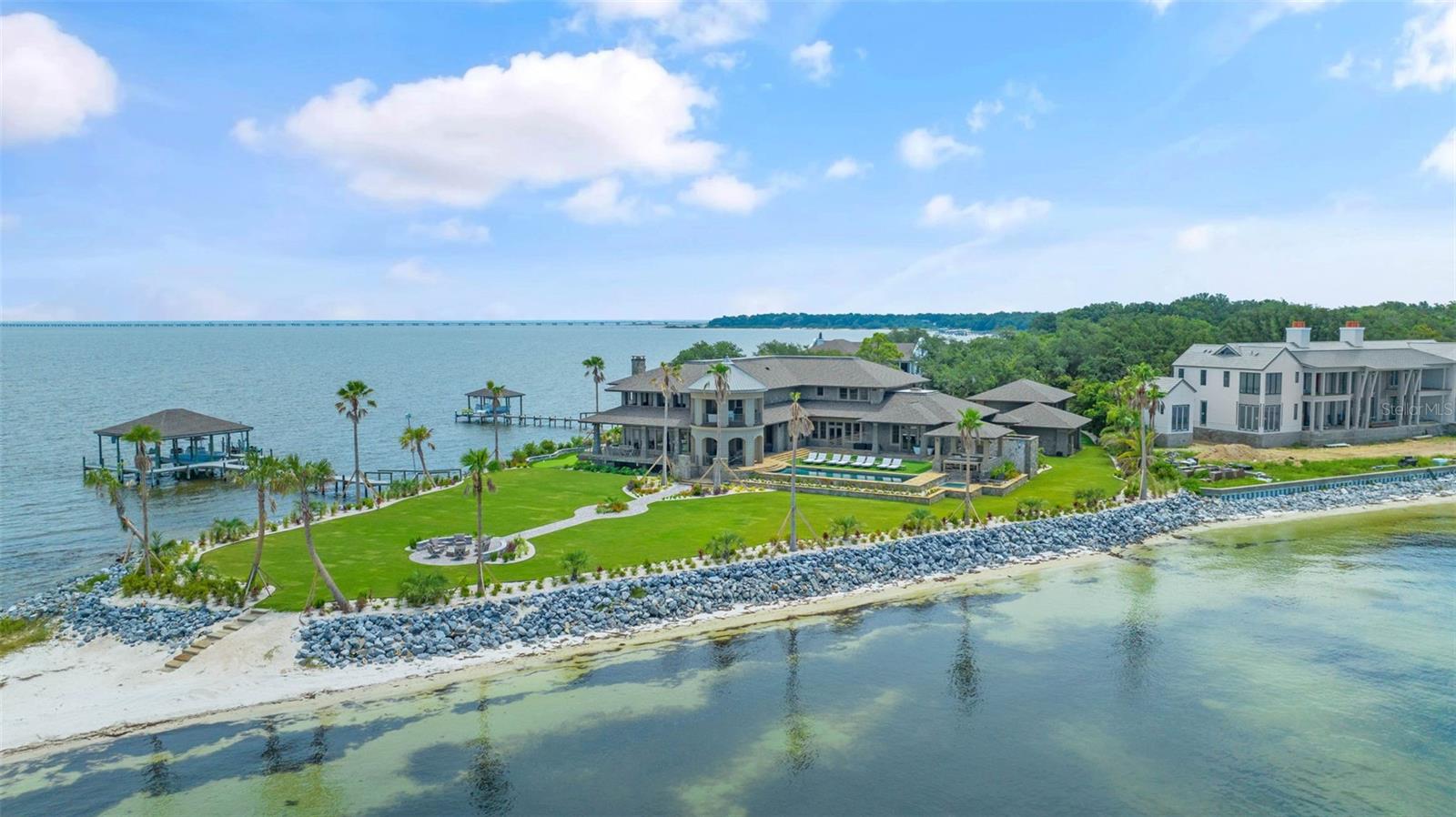 Introducing an unparalleled waterfront sanctuary in Gulf Breeze, Florida! Situated on a coveted western-facing tip lot, this luxurious estate offers ultimate privacy and opulence. With over 12,000 square feet of living space and 1000 feet of water frontage, this home epitomizes waterfront luxury. 

On the lower level, you’ll find a luxurious home theater designed for ultimate cinematic enjoyment. Nearby, a beautifully appointed bedroom suite and a spa-like bathroom offer a serene retreat. The sophisticated office provides a perfect workspace, while the well-equipped gym supports your fitness goals.
 
The expansive great room, flooded with natural light, showcases stunning views of the water and the meticulously maintained putting green, creating a perfect setting for relaxation and entertaining. Marvel at the panoramic 300° views of Pensacola Bay from every angle of the residence. 

With breathtaking water views, the primary suite features a massive walk-in closet and a spa-like ensuite with both indoor and outdoor showers for ultimate privacy. A built-in espresso machine adds luxury and convenience, creating a serene retreat that blends comfort, elegance, and tranquility.

Outdoor enthusiasts will delight in the array of amenities, including a putting green, underground trampoline, boat and jet ski lift, private beach, and upgraded landscaping. Say goodbye to pesky bugs with the underground mosquito mister while you enjoy the saltwater pool and spa overlooking the serene waters. Entertain with ease in the outdoor kitchen, perfectly positioned to take advantage of the breathtaking views. 

A detached apartment provides additional living space, complete with a full kitchen, bath, bedroom, washer, dryer and balcony, ideal for guests or extended family. This one-of-a-kind home offers a rare opportunity to experience waterfront living at its finest. Embrace the Gulf Breeze lifestyle in this exquisite retreat, where luxury meets tranquility.