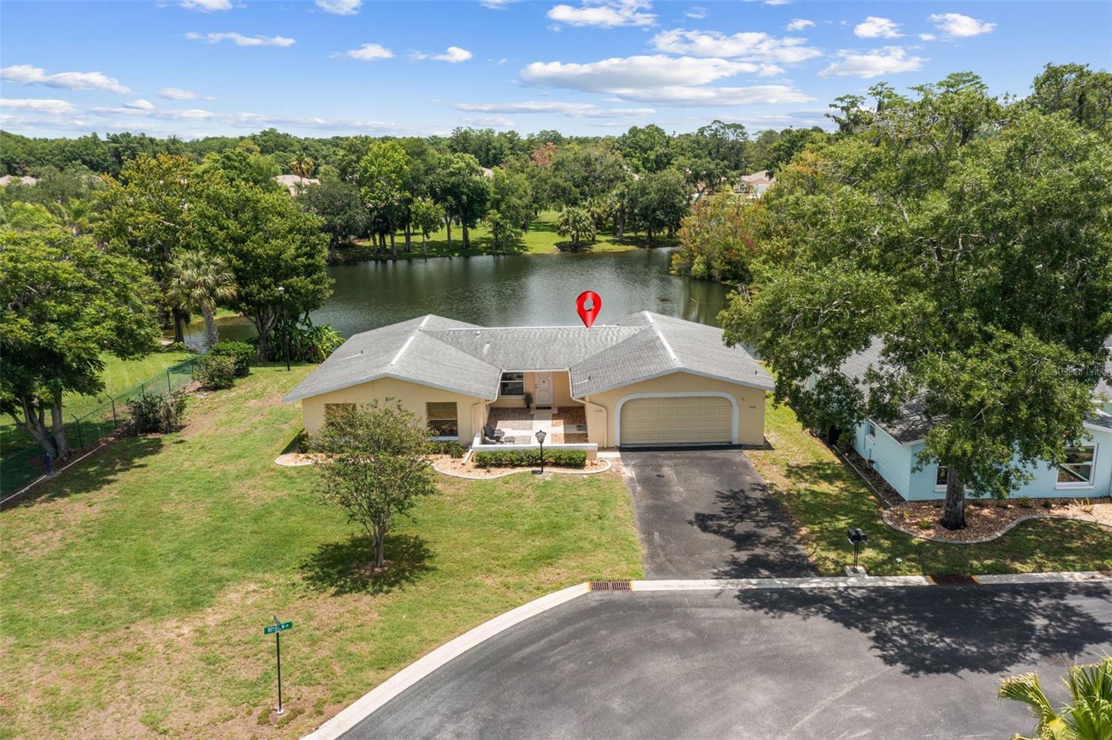 SERENE POND VIEWS | UPDATED INTERIOR | 55+ COMMUNITY LIVING! Welcome to this beautifully maintained 1 bedroom, 1.5 bath home located in New Port Richey and perfectly situated on a peaceful pond setting. Enjoy relaxing water views from multiple rooms throughout the home! This charming property also features a welcoming front patio area, perfect for enjoying your morning coffee or relaxing outdoors. Step inside to find laminate flooring flowing through the living room, dining area, and bedroom. The spacious living room features newer double-pane sliding glass doors leading to the lanai, creating plenty of natural light and seamless indoor-outdoor living. The enclosed lanai overlooks the tranquil pond and is equipped with both windows and screens, allowing you to enjoy the space comfortably year-round. The lanai was also updated in 2017. The dining area also offers lovely pond views through its large window, while the updated kitchen features stainless steel appliances and modern finishes. The bedroom includes laminate flooring, double closets, and two windows overlooking the water for a peaceful retreat. The en suite bath has been beautifully remodeled with tile flooring, a tiled walk-in shower with elegant glass doors, updated vanity, and newer showerhead. A conveniently located half bath and hallway storage closet add additional functionality. The garage offers attic pull-down stairs for extra storage, a utility sink, storage closet, and washer and dryer. Additional features and updates include gutters and downspouts, underground utilities, nearby fire hydrant, double-pane windows replaced in 2015, updated electrical panel in 2023, and a 2018 roof. Located in a desirable 55+ community offering exceptional amenities including a clubhouse, pool, tennis courts, library, shuffleboard, fitness center, pool tables, and a 9-hole golf course. The monthly fee includes trash service, cable, internet, use of all SummerTree recreational facilities, exterior maintenance, exterior painting, and roof maintenance, making for easy, low-maintenance Florida living. Conveniently located close to shopping, restaurants, medical facilities, airports, and Florida’s beautiful beaches, this home offers both comfort and convenience in a wonderful community setting. Whether you are looking for a full-time residence or seasonal retreat, this charming pond-front home is a must see!