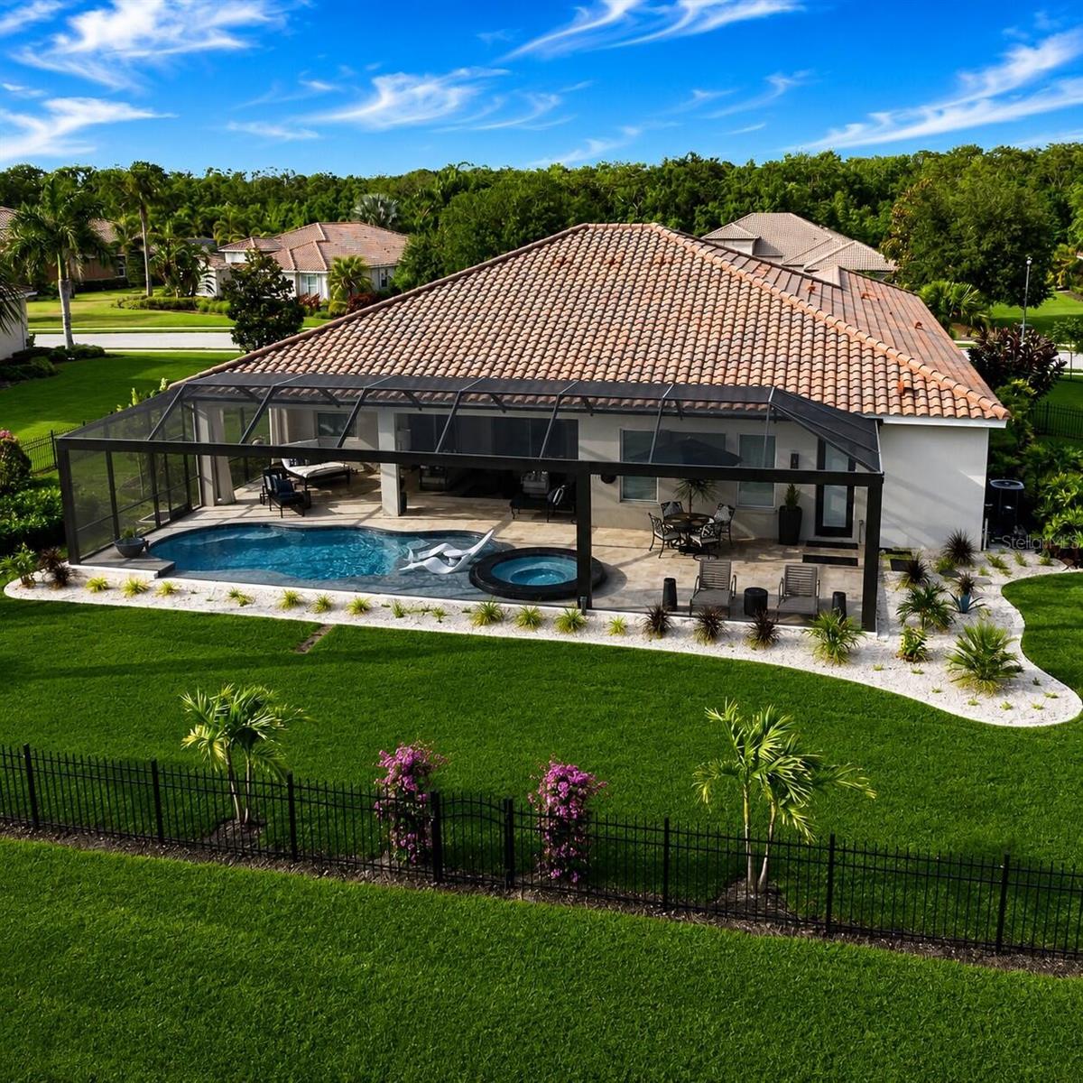 Virtually Staged. Situated on a private half-acre waterfront homesite within the custom and semi-custom home phase of Rye Wilderness Estates, this meticulously maintained residence presents a rare combination of luxury, privacy, and resort-inspired outdoor living. 

The recent custom designed outdoor living area is truly a retreat. A massive, clear view panoramic screened and covered lanai area with over 1200sf creates a private resort-style setting with wide water views, a stunning saltwater pool, custom glass tiled champagne spa, numerous water features, large glass tiled sun shelf, covered seating areas, upgraded outdoor fans, tropical landscaping, and a tranquil setting. Mature palms give the property presence along with extensive modern black aluminum fencing surrounding the rear of the property.

Whether relaxing at sunset, entertaining guests, or enjoying Florida living year-round, this backyard feels like a private retreat.

Inside, the thoughtfully updated floorplan you'll find 4 bedrooms, a dedicated home office with glass barn doors, dedicated flex/workout room, custom drop zone laundry with built-in cabinetry, cubbies, cushioned bench and beautiful copper sink, custom closet shelving, luxury vinyl flooring, quartz surfaces and designer lighting throughout—creating a turnkey lifestyle rarely found in this price range.

Designed for both everyday comfort and elevated entertaining, the home showcases an open-concept living area with abundant natural light, upgraded lighting, neutral designer finishes, and seamless views to the outdoor living space. The kitchen is a standout with quartz countertops, two tone cabinetry, stainless steel appliances, a statement island, gorgeous, upgraded chandeliers, and stylish pendant lighting.

The primary suite is a private retreat with generous space, pool access, upgraded luxury wood look flooring, and a spa-inspired bath with dual vanities, soaking tub, walk-in shower, and modern black fixtures. Additional bedrooms are well-appointed with wood-look flooring.

This is a rare opportunity to own a thoughtfully upgraded home in one of the more custom-feeling sections of Rye Wilderness Estates, with impressive indoor living, exceptional resort-style outdoor space, and the elevated finishes you are looking for! Some photos have been virtually rendered.