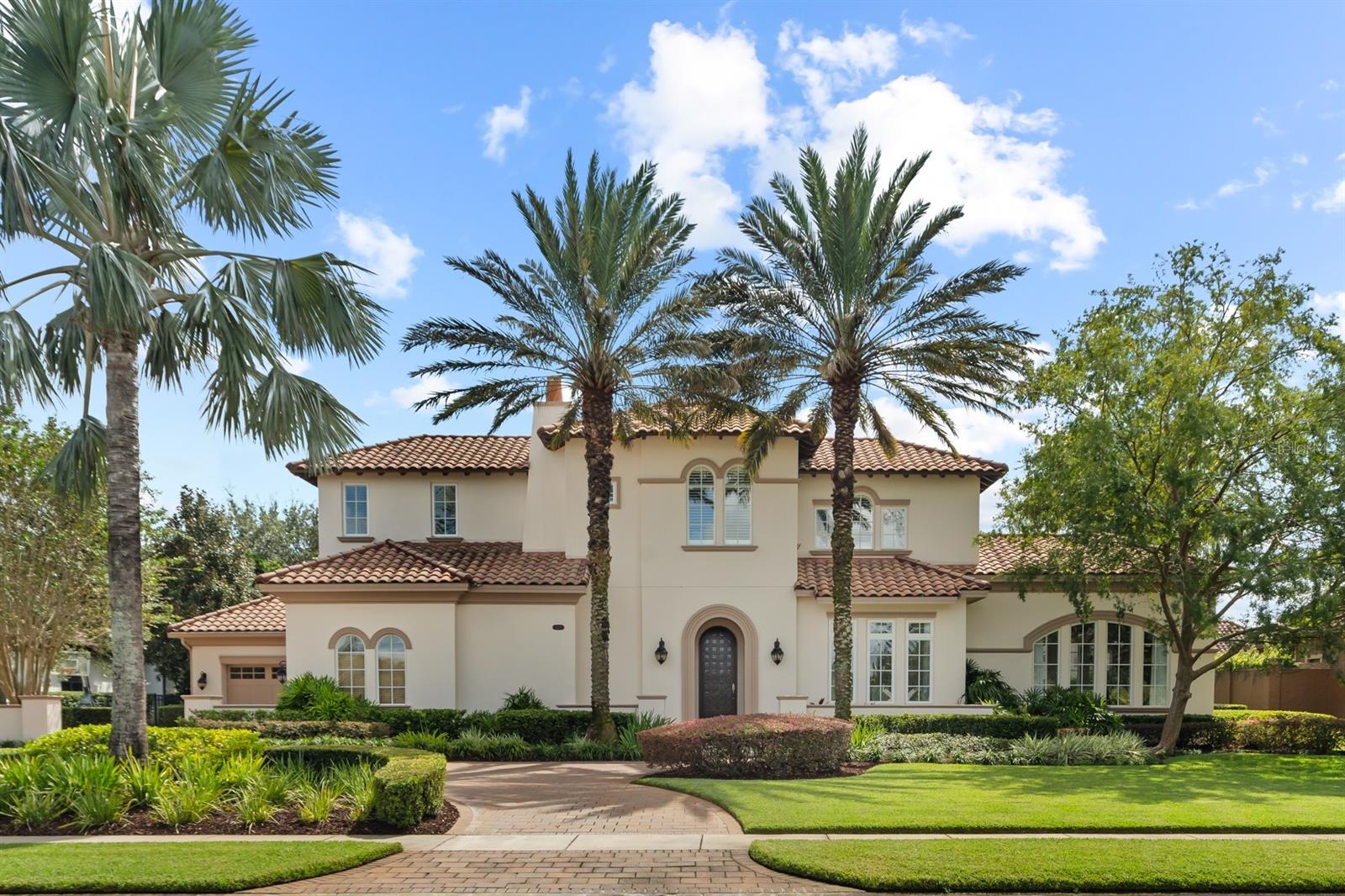 "Casa Amare," built by Master Custom Builder Castleworks who is most known for their unique style and quality construction. This courtyard-style home, which embodies timeless modern design, is situated on a 3/4 acre lot within the prestigious 24-hour guard gated community of Bellaria. Recently revitalized landscaping greets you as you cross the travertine walkway over a water feature which frames the entry way and sets a spa-like feel as you step through the custom solid wood door with decorative glass inlays. This unique floorplan features numerous retractable glass sliding doors throughout to make the indoor and outdoor spaces blend seamlessly for entertaining. The entire home boasts sleek travertine flooring on the first floor and warm walnut wood flooring on the second. To the right of the entry way is the glamourous formal dining room highlighted by a custom light fixture with woven wood details and accent tile flooring creating a dramatic setting for lavish dinner parties. Separated by a wet bar with wine refrigerator, the adjacent formal living room creates a striking backdrop for formal gatherings with a wood and stainless-steel tray ceiling, and custom basket-weave wood paneled accent wall. The kitchen is a chef’s dream with Viking and Miele appliances, solid wood cabinetry, hidden walk-in pantry and an oversized center island/breakfast bar. Open to the kitchen, the family room is anchored by a remarkable steel accented fireplace that is flanked by sliding glass doors that allow you to enjoy views of the courtyard-style pool. A dramatic cascading pool fountain provides relaxing ambiance in the fully enclosed pool area with travertine patio, heated pool and spa, outdoor fireplace, and an oversized summer kitchen providing you with the ultimate resort lifestyle. The master suite is exceptional with a separate sitting room, wood panel accent wall, and spa-like bath with Kohler's ceiling faucet into a "vanishing edge" jetted tub, glass enclosure walk-in shower, separate vanities, and a generously sized walk-in closet with custom, built-in organization system. The first floor, guest bedroom is currently a custom closet with an easy conversion back if desired. The second floor offers 3 bedrooms each with their own en-suite bathrooms, walk-in closets, and a shared study loft. The enormous backyard features shade trees and a paver patio framed by beautifully manicured hedges. The community of Bellaria offers the convenience of being just minutes from Winter Garden Village, A+ schools, top area attractions, and easy access to major roadways!
