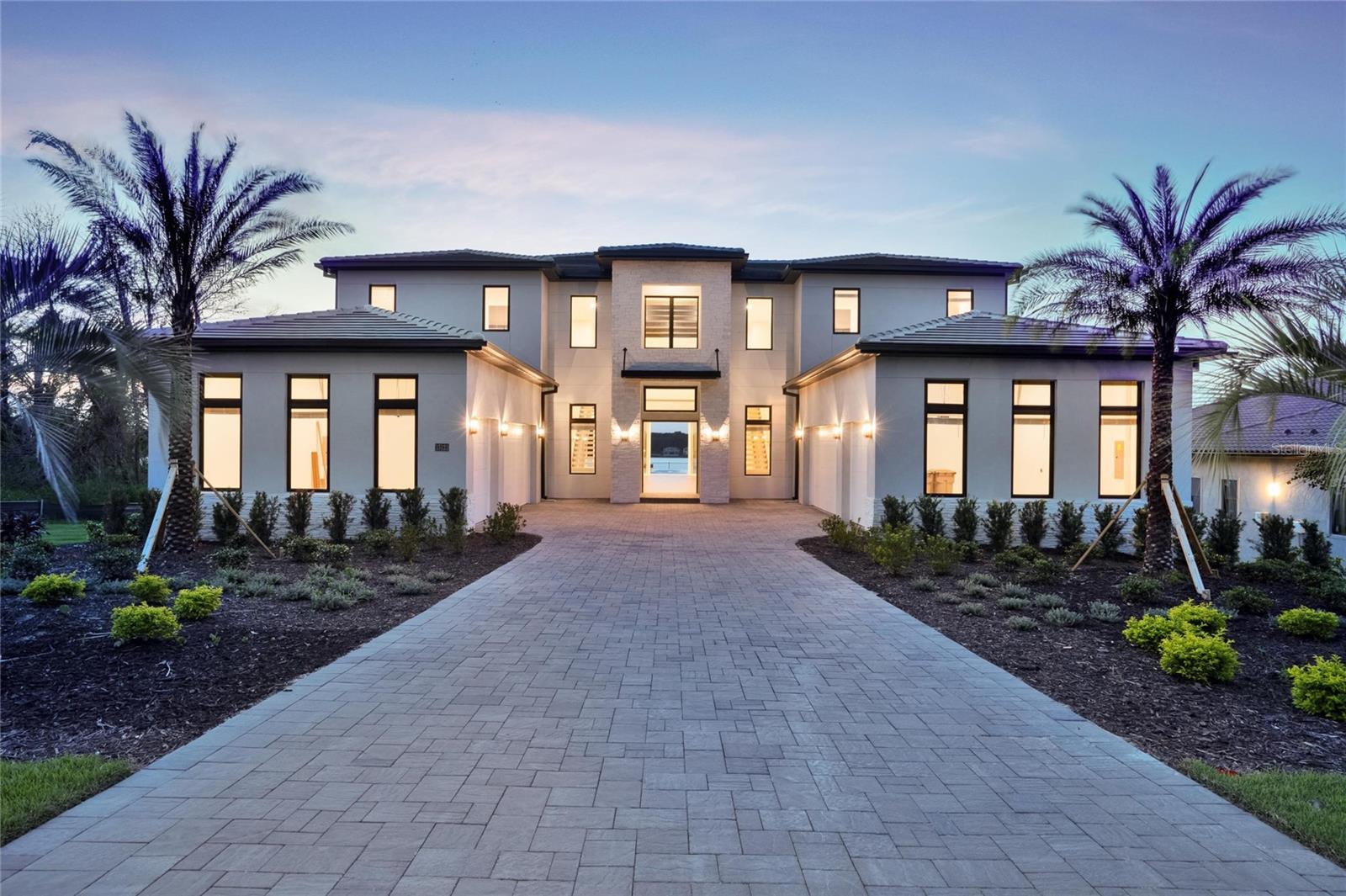 STAND OUT FROM THE ORIDNARY and elevate your lifestyle into the breathtaking realm of Bella Collina! Introducing a newly constructed luxury lakefront residence highly positioned on an expansive acre-plus lot in the exclusive Estates section of the community. Overlooking the serene shores of Lake Sienna, this exceptional home offers panoramic water views, sophisticated interior finishes, and an ultra-impressive outdoor living space designed for both relaxation and entertaining. This is more than just a home, it’s a statement of purpose and meaning. From the moment you step through the covered entry, you’re met with dramatic architectural elements including double floating staircases, a soaring two-story open concept gathering space and uninterrupted sightlines to captivating lake views. The main level has been thoughtfully designed for both convenience and everyday living and features a grand, open concept living, dining, and kitchen area, a luxurious primary suite with lake views, a secondary en-suite bedroom, a versatile flex room, powder bath, large laundry room, and a practical drop zone off one of two oversized three-car garages. Upstairs, a walkway bridge for added privacy separates three additional en-suite bedrooms, a private home office, and a spacious loft and media room prewired with multiple Cat 6 outlets for today’s connected lifestyle. What truly sets this home apart is the outdoor living area with a spacious travertine deck, high ceiling covered lanai, fully equipped summer kitchen, gas fireplace, and a dedicated pool bath and shower - all framed by picturesque water views. The custom-designed infinity-edge pool is flanked by two raised pedestal mounts ideal for fire bowls or water features. A multi-person heated spa and sun shelf invite tranquil moments under the sun.
A stately cascading staircase leads to a lower-level retreat with artificial turf and aluminum fencing—prime for a fire pit or lounging area. A second terraced area below takes you down to a sprawling backyard with over 140 feet of shoreline. Planning to bring your boat? This is one of the select properties that can accommodate a private dock. Completed in April and awaiting your personal touch, this home is an extraordinary opportunity to own in one of Florida’s most prestigious guard-gated, golf communities. Bella Collina spans over 2000 acres and is truly a one-of-a-kind compelling setting from awe-inspiring scenery and topography to a collection of striking homes of distinction offering an unmatched lifestyle for those wanting luxury lakefront living. Highlights of the features and amenities include a Tuscan-inspired hilltop village showcasing a world-class 75,000 square foot clubhouse, ballroom, full-service spa, restaurants and bars. There are also tennis, pickleball courts, a state-of-the-art fitness center, resort-style pool w/ lap lanes, dog park and even a heli-pad. It is conveniently located within easy reach of Orlando International Airport, downtown Orlando, the town centers of Winter Garden, Clermont, Minneola, and the highly anticipated Olympus Project in Wellness Way. Outdoor enthusiasts will love the West Orange Trail just a few miles away. Top rated schools, hospitals, shopping, and dining are close by. Theme parks are a short easy drive... Whether you're seeking an upscale, active way of life filled with social aspects and a variety of choice activities, or a peaceful haven of refined living, 15121 Pendio delivers it all.