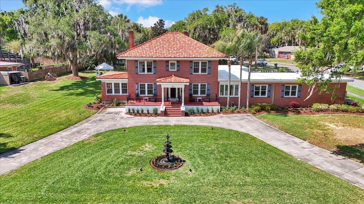 A rare opportunity to own one of Leesburg’s iconic lakefront estates, offering 164 feet of direct frontage on Lake Harris and set on a beautifully positioned 1.24-acre corner lot. This exceptional property delivers unmatched curb appeal with its stately presence, circular drive, mature landscaping and timeless architectural charm. The main residence spans nearly 5,000 square feet and has been thoughtfully updated to blend classic elegance with modern comfort. The 2020-renovated kitchen serves as the heart of the home, complemented by updated bathrooms throughout. Offering five bedrooms and 4.5 baths, the layout is ideal for everyday living and hosting guests. A private mother-in-law suite with its own fully equipped kitchen provides flexibility for extended family or long-term guests, while a detached efficiency apartment above the garage creates additional living space or an excellent income-producing opportunity. Designed for relaxation and recreation, the outdoor living experience is resort-style. Enjoy a recently renovated heated pool and spa, expansive patio areas, and sweeping lake views that create a backdrop for entertaining or quiet evenings at home. The private boathouse with dock and lift provides effortless access to the Harris Chain of Lakes, making this a dream setting for boating enthusiasts. Within city limits in a golf cart-friendly area, the home offers a blend of privacy and convenience, just minutes from downtown Leesburg dining, shopping and waterfront parks. With its expansive homesite, impressive 164 feet of shoreline and premier lakefront amenities, this is a one-of-a-kind offering that captures the best of Florida waterfront living.