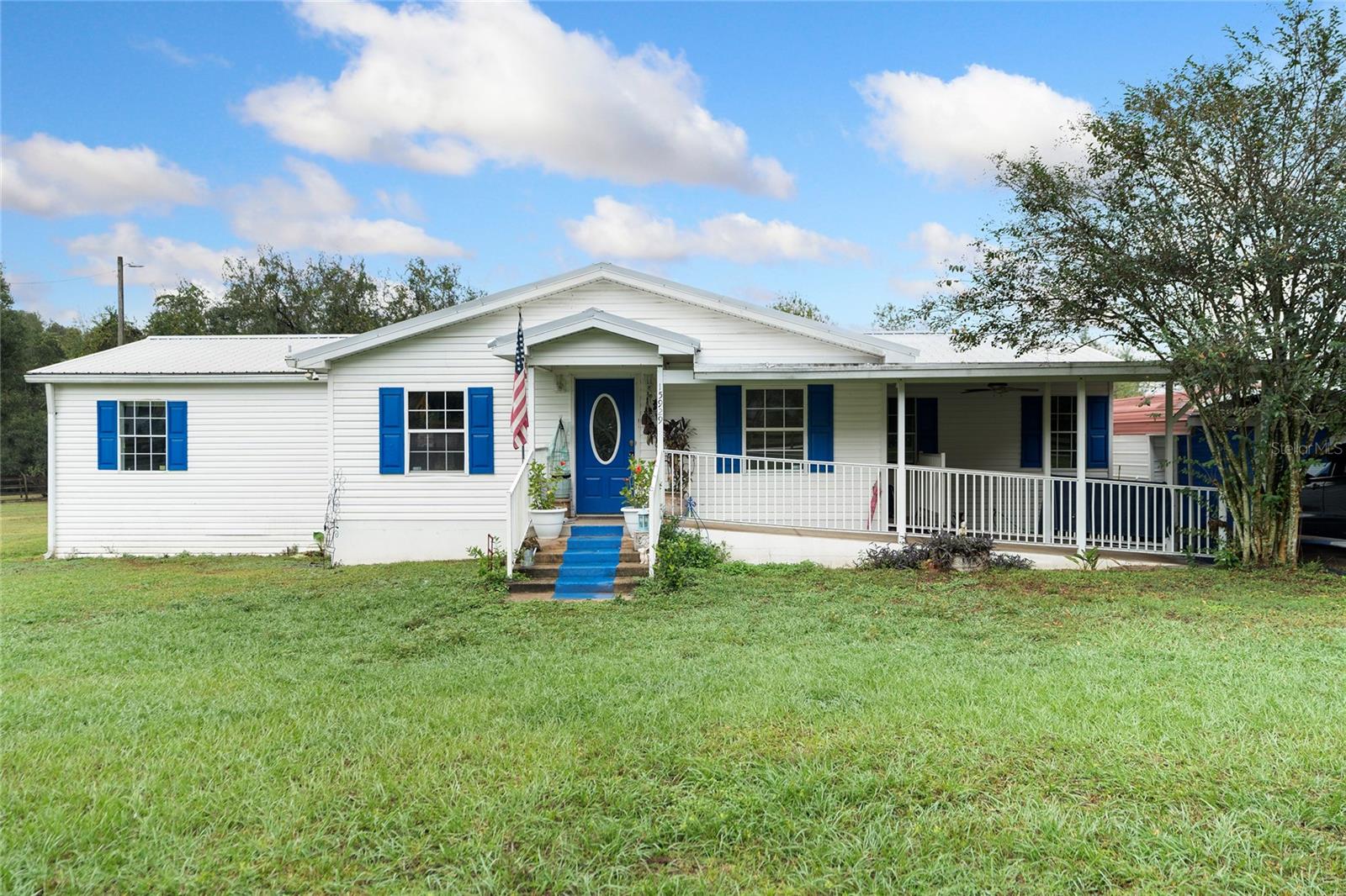 This double-wide mobile home is situated on a sprawling 1.01 acres of beautifully cleared land, offering a serene and spacious living environment. The property features a convenient carport, complete with a ramp leading up to the front door, all seamlessly connected under a single structure that includes a small front porch and an inviting awning at the entrance.

Inside, the home boasts three bedrooms and two bathrooms, designed to accommodate both comfort and functionality. The master bedroom is a true retreat, featuring an en-suite master bathroom equipped with his-and-hers sinks, a luxurious soaking tub, and a spacious walk-in shower. Bedroom 2 is enhanced by a walk-in closet, while Bedroom 3 offers a built-in closet. These rooms share the second bathroom, which is fitted with a practical shower-tub combination.

The living spaces are defined by an open floor concept, seamlessly connecting the living room and dining area with the family room located near the entrance. The kitchen is a focal point of the home, featuring a breakfast bar and two serving windows that add to its functionality and charm. Natural light floods the space through the numerous windows, offering stunning views of the surrounding property.

The back of the home opens up to a covered porch, leading to a dedicated dog run, perfect for pet owners. Additionally, there's a garage located behind the carport, providing ample space for additional parking tools and equipment. The entire property is fenced, ensuring privacy and security.

Notably, this property is free from the constraints of Homeowners Association (HOA) or Community Development District (CDD) fees, adding to its appeal for those seeking a peaceful and unrestricted living experience.