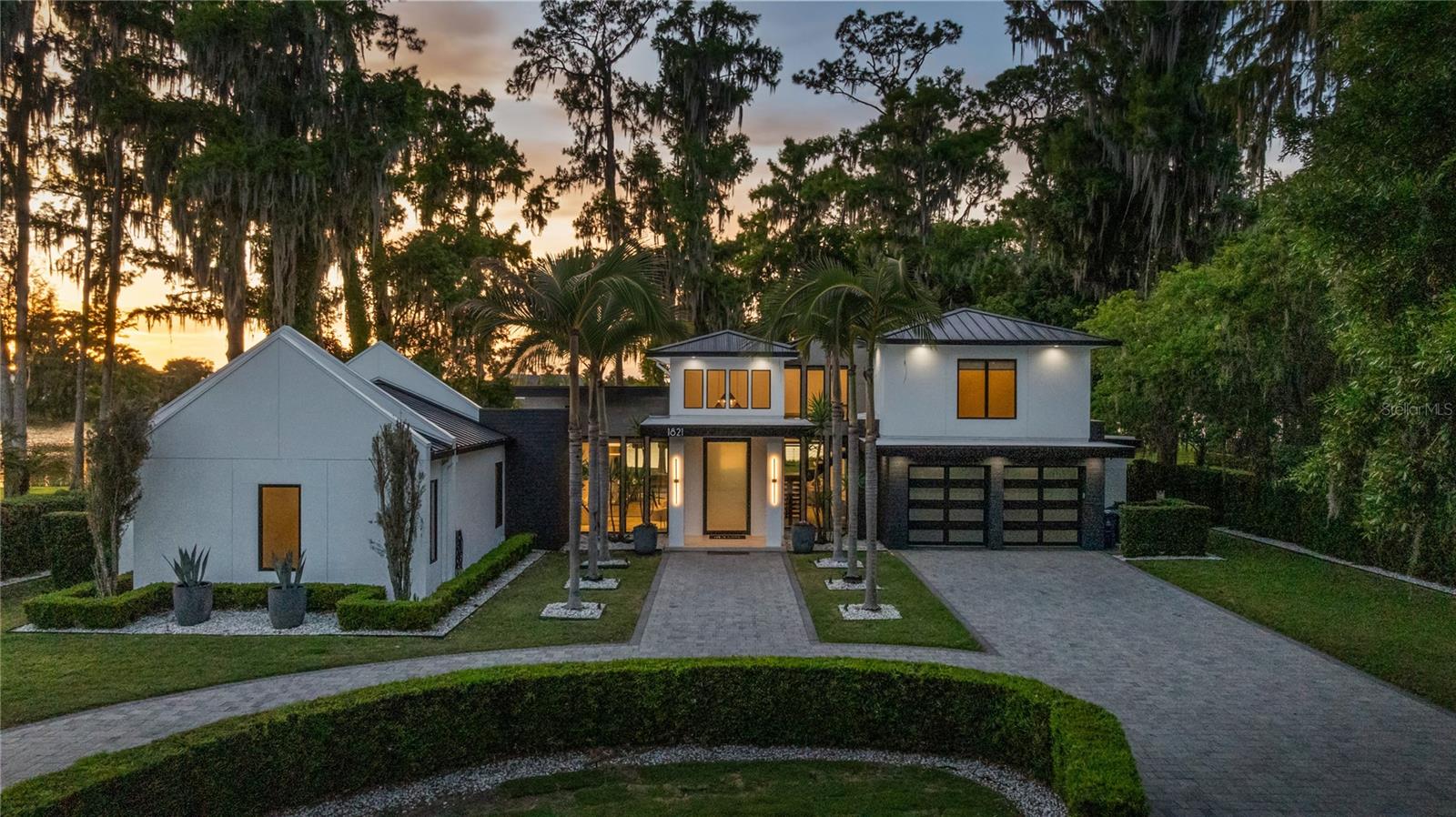 Set on over half an acre along the shores of Lake Maitland in the heart of the coveted Vias, this exceptional residence by Modish Homes is both a former 2018 Parade of Homes winner and a standout example of Winter Park luxury living. From the moment you enter, a dramatic two-story foyer sets the tone, drawing your eye through to the main living space where a statement wood-burning fireplace anchors the room and expansive glass frames breathtaking views of the water beyond. Every space has been thoughtfully designed to maximize both scale and sightlines, creating an effortless connection between indoors and the natural beauty outside. The home features touches of Walnut floors, detailing and doors, bringing warmth throughout. At the center of the home, the chef’s kitchen is both refined and functional, featuring custom cabinetry, a full suite of Dacor appliances, and an oversized walk-in pantry. A striking wet bar with a glass wine wall adds a layer of sophistication, ideal for entertaining. The dining room is equally impressive, offering panoramic lake views and seamless access to the outdoor living areas. The main-level primary suite is a true private retreat, highlighted by chevron-pattern tile flooring and a spa-inspired bath complete with dual vanities, designer lighting, a freestanding soaking tub, and an expansive walk-in shower. The main level also includes two additional guest suites and a glass-enclosed office, offering both comfort and flexibility. Upstairs, two more bedrooms are complemented by a spacious loft and a large balcony that captures sweeping views of the lake. Designed to rival a private resort, the outdoor living experience is nothing short of exceptional. A fully equipped summer kitchen, resort-style pool and spa, two outdoor showers, and expansive green space create a setting that is both functional and visually stunning. A private viewing dock overlooks the water or reconfigure it to a boat dock, allowing you to fully embrace life on the lake while enjoying views of the iconic Isle of Sicily. Beyond the property, the lifestyle is equally compelling. Additional features include a full Control4 home automation system, sauna, and an expansive double-entry driveway providing ample parking. Located just minutes from the boutiques, dining, and cafés of Park Avenue, and within close proximity to Kraft Azalea Garden and the Winter Park Racquet Ball Club, this home offers the perfect balance of privacy and convenience. This is truly a one-of-a-kind opportunity to own a true showpiece on the Winter Park Chain of Lakes.