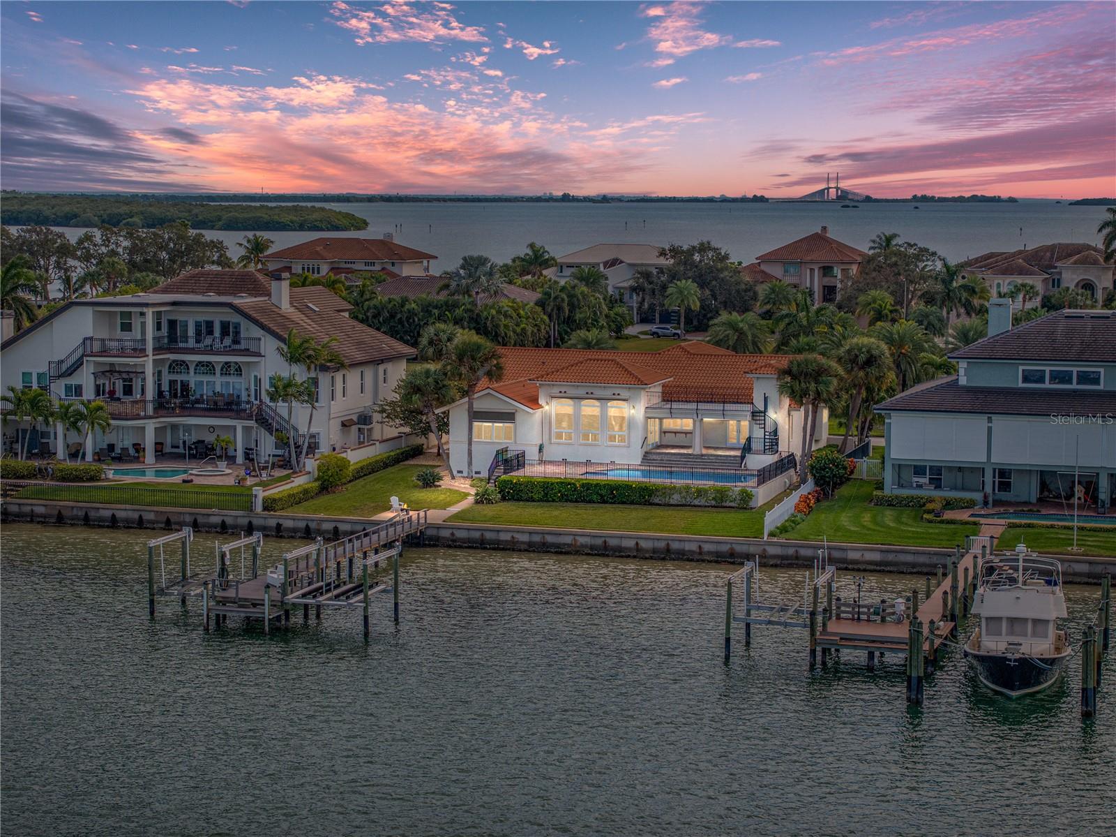 The Bayway Isles Community website boasts: “Two Islands & Four Lakes: Where the water meets the land and boats out number people. Location, Location, Location! Sunsets across the water and Paradise without the travel!” THEY ARE NOT WRONG!  Strategically positioned minutes from the beach whether by car or boat in the sought-after Bayway Isles II gated-community on not “Million-Dollar Row, but MULTI-MILLION DOLLAR ROW, you will find this Mediterranean-style gem! And while the home is formidable and in tip-top condition, it is the lot that will captivate your heart! Measuring 140 feet deep and sporting 100’ of water frontage on a quiet bay, with impressive docking facilities, the land alone is worth the asking price!  The dock has two lifts (10K & 13K) and all the dockside amenities that you both want and need! Other homes currently for sale in Bayway Isles II range from $6,595,000 to $7,500,000! Recent sales in the neighborhood have been between $2,750,000 and $6,300,000! Why? Because the community is impeccably maintained, conveniently located, and enjoys fabulous waterfront views. Indeed, from the front door to the pristine, white sand of #1-Rated Pass a Grille/ St Pete Beach is less than a 10-minute drive! And, if you are looking for a plethora of dining and entertainment options, venture less than 15-minutes by car to the  exciting ‘Riviera-esque’ nightlife, dining, cultural options and people-watching that defines Beach Drive and Downtown St. Pete! The home at over 3200acsf and more than 4000sf total, has 4 bedrooms + an office, 4.5 bathrooms, and a 3-car garage with additional storage. The great outdoors here has recently enjoyed a refresh with new pavers to the elevated patio poolside, as well as to the pool deck and surrounding areas. The pool is heated for your winter enjoyment; and when the sun is blazing down, you can turn on your pool chiller and enjoy a refreshing dip! AND, there is a second, third-level deck that is accessed via the exterior spiral staircase that enjoys simply incredible panoramic views looking north from east to west. All of this AND more is here and move-in ready for you and yours to realize your dream lifestyle in Bayway Isles II!