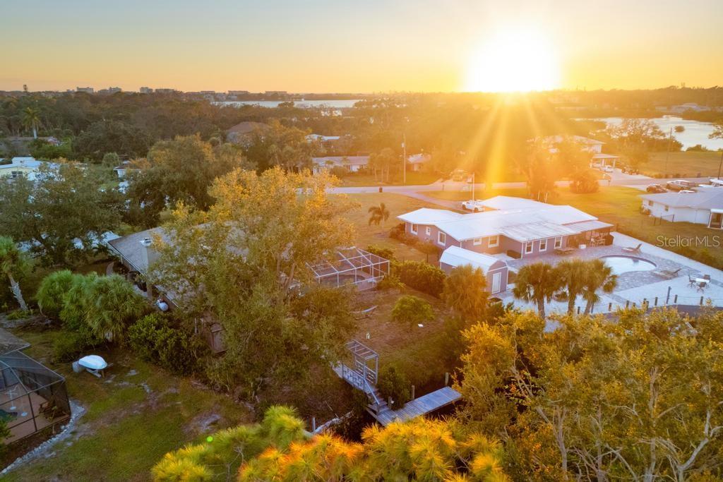 This special, one of a kind home has quick access to Dona Bay and then the beautiful ocean waters of the Gulf. This home is exceptionally elevated at more than 11 feet, keeping it high and dry and solid through storm season with zero flooding over the years. The inviting layout features 3 bedrooms, 3 bathrooms and a heated saltwater pool on a spacious, nearly half-acre lot shaded by stunning mature oaks and fruit trees. 
Interior highlights include fresh, light and bright paint, rich wood-look plank floors, vaulted ceilings, and a cozy woodburning indoor fireplace. The fully remodeled gourmet kitchen includes gorgeous Quartzite countertops, stainless appliances, solid-wood cabinets, built-in espresso maker, and a charming custom wine room for the wine connoisseur. Views of the relaxing pool deck with an outdoor kitchen from nearly every angle.
The primary suite features pool access, custom walk-in closets, and a spa-like ensuite bath with a beautiful Spanish marble soaker tub, dual sinks and tiled shower. The split bedroom floorplan affords privacy and convenience for the second and third bedrooms, and the third bedroom features a private ensuite bathroom and pool access. The full guest bathroom also features pool access.
The outdoor oasis includes a caged lanai with a saltwater, heated pool, outdoor kitchen, and a unique custom-built fire pit area. Follow the path to the dock and seawall, and imagine your own boat waiting to take you out for a fun day on the Gulf. Oversized 2-car garage has epoxy floors and upgraded modern storage cabinets with a tool bench. Truly a unique and charming waterfront escape located conveniently near historic downtown Venice, Venice Beach, Nokomis Beach, and Casey Key. Travel a short distance north for all of the amenities of Sarasota, including an exciting downtown district, Siesta Key Beach, performing arts venues, and luxury dining and shopping.