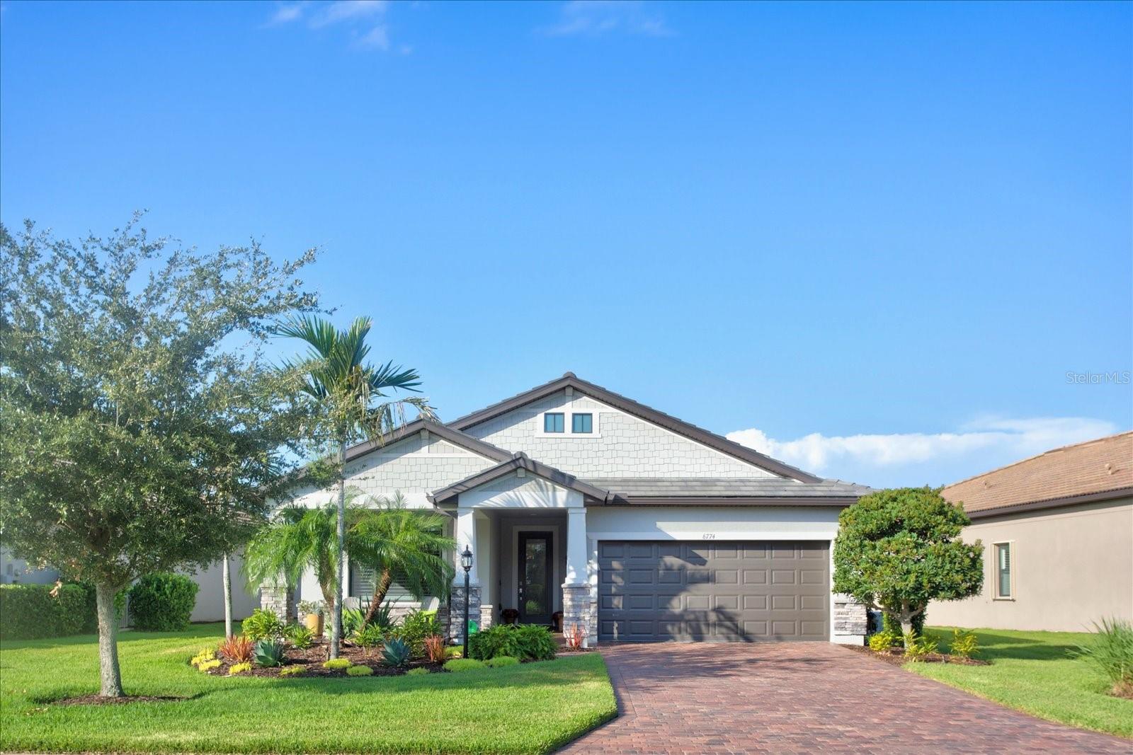 Welcome to your move-in ready Craftsman retreat on a stunning water view lot with ideal north-south exposure and located in the highly sought-after 55+ community Del Webb nestled within Lakewood Ranch. Impeccably maintained and thoughtfully upgraded throughout, this home offers exceptional curb appeal with a welcoming extended front porch, natural stone accents, and professionally designed landscaping with integrated lighting. Step inside to bright, neutral plank tile floors, 8-foot interior doors, 5-inch baseboards, plantation shutters, upgraded lighting and designer accent walls. The heart of the home is an oversized kitchen island with end cabinets, abundant storage including custom closets and pantry, plus a convenient laundry room with cabinets and folding counter. A custom office with built-ins offers a polished work from home space. Relax and entertain on the extended lanai with Kevlar remote-controlled screens and water views or rely on whole home comforts like a generator, hurricane impact windows, whole-home reverse osmosis water filtration system, ceiling fans, and a modern security system with rear floodlights. The owner’s suite and guest bath feature Kohler shower head and handheld, frameless shower enclosure, grab bars, and custom framed mirrors for a spa-like finish. Practical upgrades include a 4-foot garage and lanai extension, pull-down attic access, garage utility sink, and a garage door opener replaced June 2025. This home blends style, safety, and smart functionality---schedule your showing today!