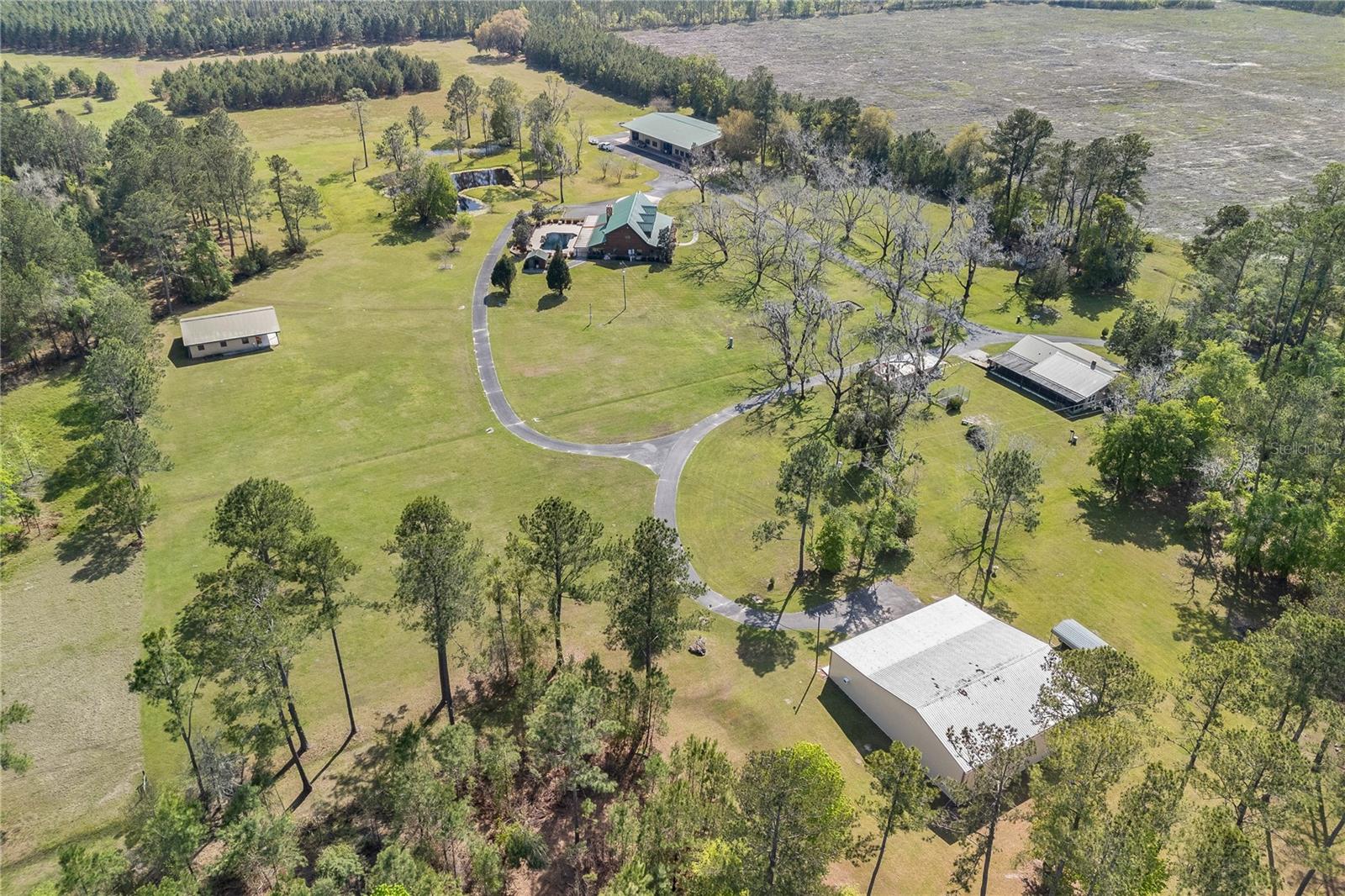 Experience the epitome of Southern living on this 242+/- acre estate located in north Florida, a sanctuary where luxury, versatility, and natural beauty converge to create an unparalleled lifestyle. Entering this expansive estate, you're greeted by the majestic main home, boasting over 5,000 sq/ft. A sprawling front porch invites you to unwind in rocking chairs while soaking in the tranquil surroundings. The open-concept layout exudes a warm and cozy lodge ambiance, perfect for gatherings or quiet evenings. The owner's suite is conveniently located on the first floor. Step outside onto the spacious back deck, where a saltwater swimming pool awaits. A stroll away from the main house, a charming secondary home awaits, updated in 2004, featuring 3br/2ba. For the aviators there is a grass landing strip, and a third living area inside the airplane hangar. The 6,000 sq/ft hangar includes a 2br/2ba apartment, a safe room, and a full bath. A 2,400-square-foot workshop provides storage and activity space, a 1/2 bath and a climatized room for comfort. Equestrian enthusiasts will delight in the separate barn, offering water and power, catering to the needs of their horses. This remarkable estate doesn't stop there; it's a true investment opportunity with income-producing leases on the pines and straw. Drip irrigation and a commercial well on the front parcel. As you explore the grounds, you'll encounter pecan trees lining the drive, mature landscaping, 3 ponds and abundant wildlife.