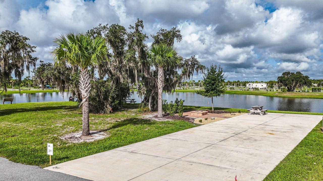 Premium corner RV lot at Resort at Canopy Oaks with relaxing water views, enhanced privacy, and only one neighboring lot. Features a custom paver patio and fire pit, plus a 20’ x 70’ concrete pad with full 20/30/50 amp hookups accommodating Class A & C motorhomes, fifth wheels, travel trailers, or a small park model. Enjoy resort amenities including tiki bar with live music, pool and spa, pickleball, putting green, and more. Perfect as a personal retreat or generate income by participating in the resort-managed rental program. Developer incentives available.