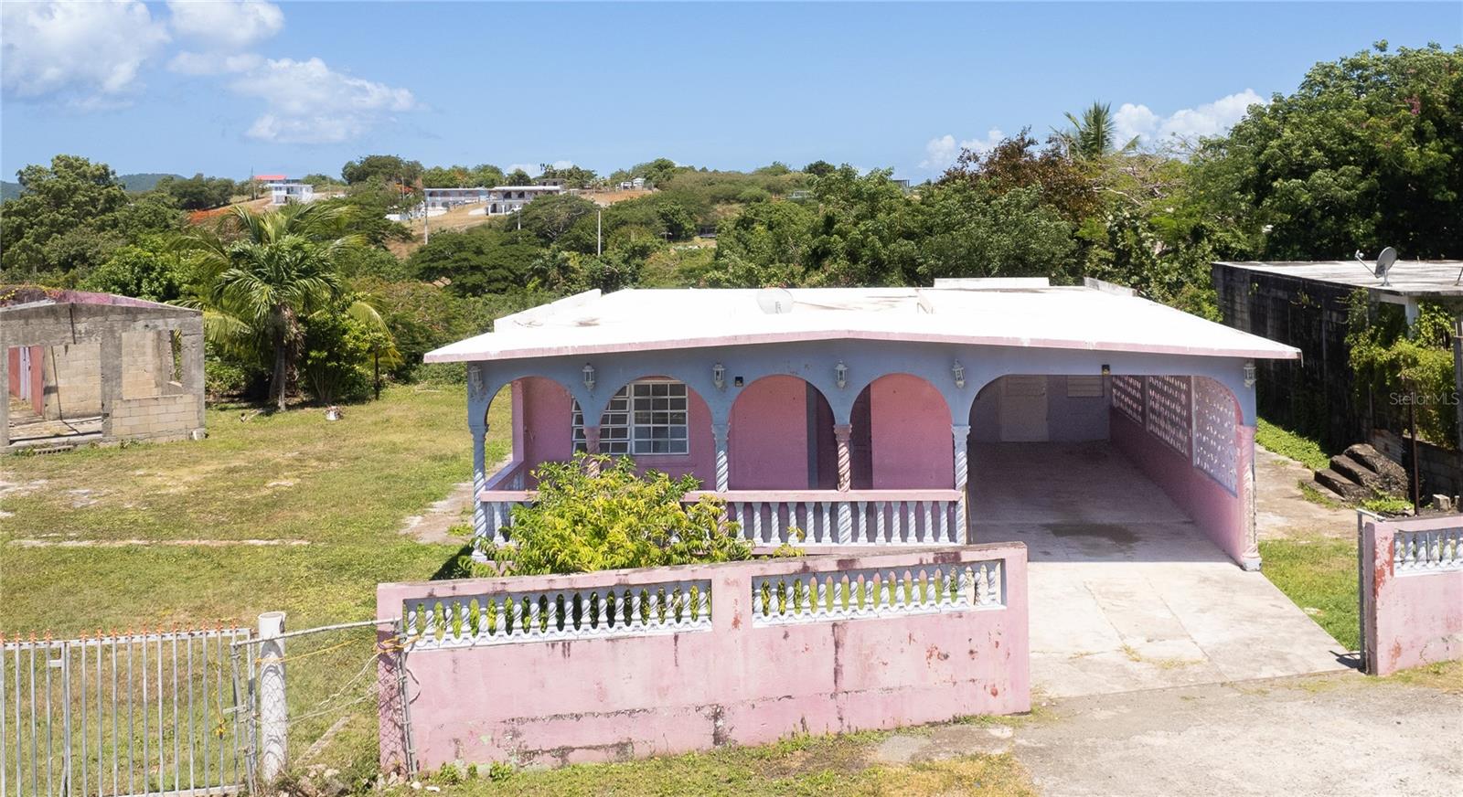 Tucked into the Bravos neighborhood and just a short walk from La Chata beach, this property offers an intriguing mix of history, space, and opportunity. Once part of a sugar mill, the main house stands solid with character and good bones — ready for someone with vision to bring it back to life. It features a bright and spacious great room, four comfortably sized bedrooms, one full bath, and a full functionally sized kitchen that’s ready for remodeling. A front balcony provides a quiet spot to enjoy morning or afternoon coffee, and the covered carport fits two vehicles with ease.

Beyond the main home, there’s a second unfinished structure set up as a 3-bedroom, 1-bath layout with its own living room, kitchen, and dedicated parking area. It will need a roof but offers a strong foundation for guest use, rental potential, or a multi-family setup.

The lot itself is over a third of an acre, with two gated entrances and plenty of space to add a pool, create a garden, or build out outdoor living areas. It’s just a short walk to La Chata beach and a three minute drive from town while still feeling tucked away in a walkable, well-known neighborhood. This is a solid property in a great location with history, substance, and room to grow.