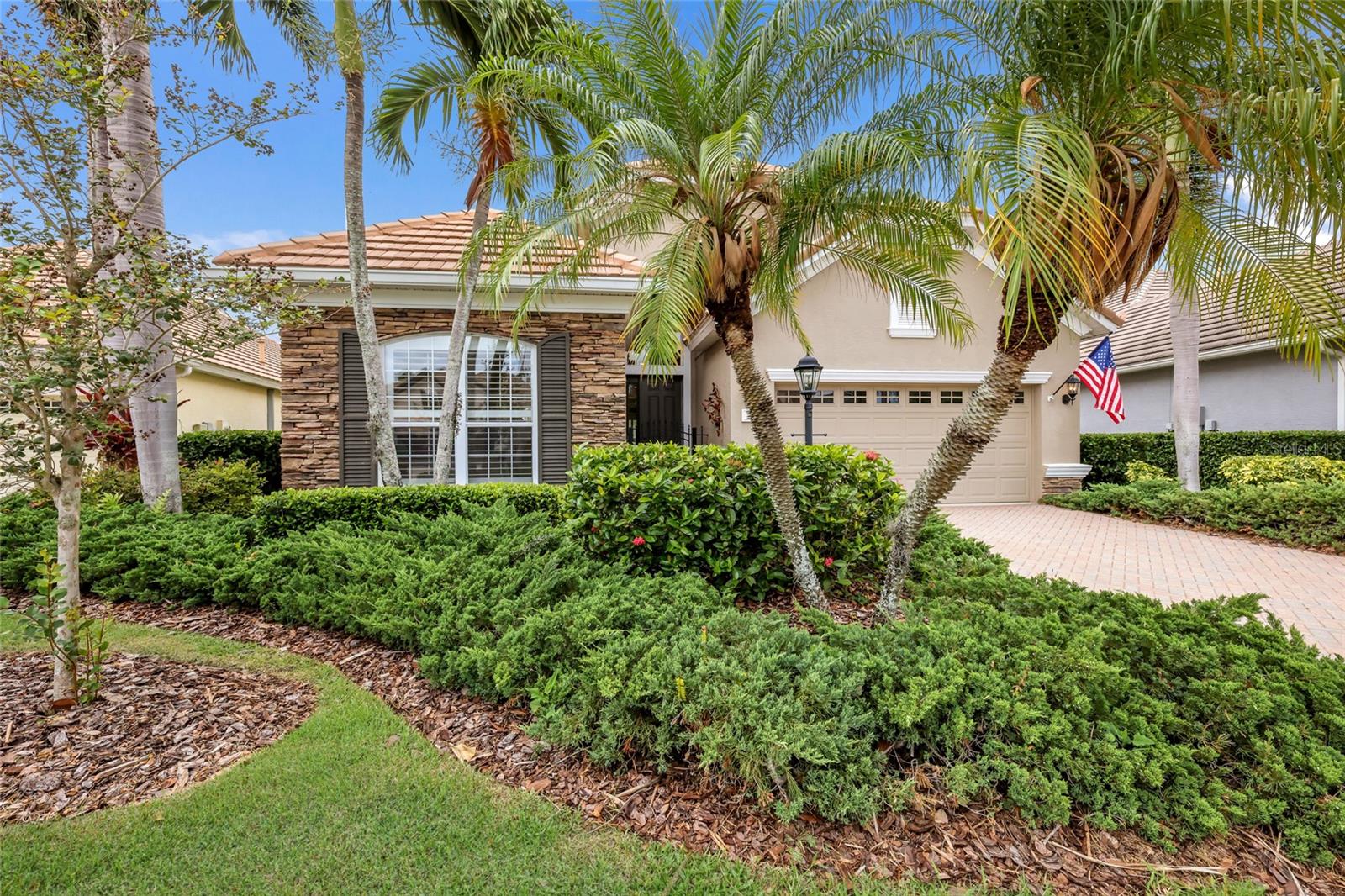Equipped with a whole-house generator, this charming and spacious 2,260 sq. ft. residence in the gated, maintenance-free enclave of Orchid Island within the Lakewood Ranch Golf & Country Club offers comfort, quality, and serene lakefront surroundings. Thoughtfully designed, the home features an expansive primary suite with a sitting area, two oversized walk-in closets, dual vanities, soaking tub, and walk-in shower, along with a generous guest en suite and a spacious den or office complete with double-door pocket entry and custom built-ins. Interior appointments include wood flooring throughout, crown moldings, and tray ceilings. A generously sized flex space positioned off the main living areas offers the perfect setting for a home office, lounge, media space, or formal entertaining. The kitchen is designed for both everyday living and entertaining with a breakfast bar, dinette, gas range, walk-in pantry, abundant counter space, and extended cabinetry. The laundry room is equally well appointed with a utility sink, a wall of built-in storage, and a built-in ironing board. Four sets of sliders span the great room, opening to a picturesque lake and treed setting with a screened paver lanai, outdoor kitchen, and tranquil fountain — creating the perfect backdrop for relaxation. The Orchid Island resident pool is conveniently located just steps away, and several levels of optional membership opportunities are available at the Lakewood Ranch Golf & Country Club.