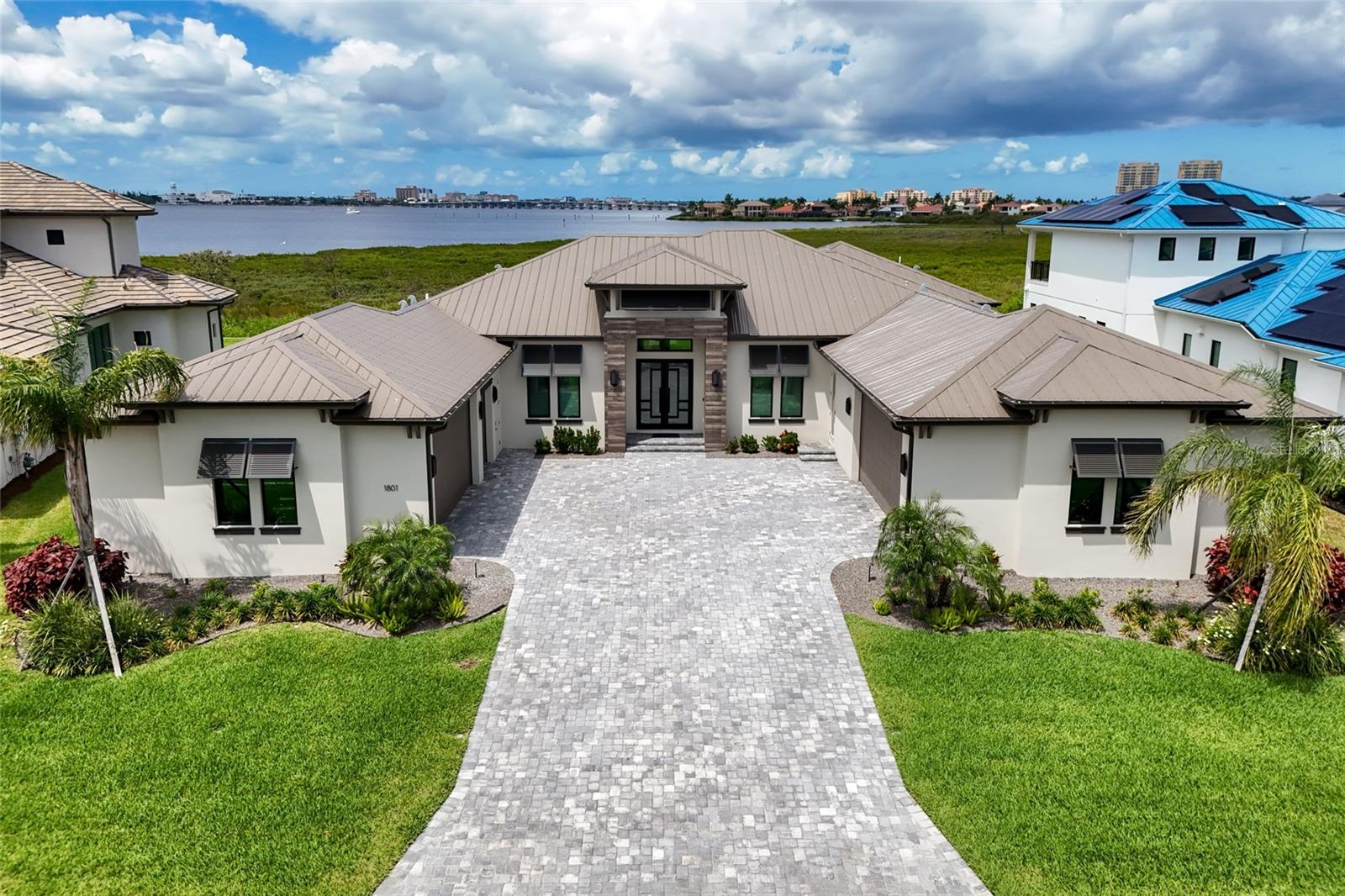 Under contract-accepting backup offers. ABSOLUTELY STUNNING 2024 custom built riverfront masterpiece by the Vision Group located inside the exclusive gated waterfront community of Sanctuary Cove in the private Waters Edge section. BEING SOLD TURNKEY FURNISHED JUST BRING YOUR BAGS! Perfectly positioned to capture breathtaking water views and unforgettable sunsets, this exceptional residence also includes a BOAT SLIP w 12,000 lb lift  offering the ultimate waterfront lifestyle. From the moment you arrive, the curb appeal is undeniable with a gorgeous metal roof, expansive paver brick driveway, modern coastal architecture, lush tropical landscaping, and an oversized 4.5 car garage designed for vehicles, golf carts, water toys, and additional storage. Step through the grand foyer and you are immediately greeted by panoramic pool and river views framed by walls of disappearing 8 foot sliding glass doors seamlessly blending indoor and outdoor living. The thoughtfully designed great room floorplan unites the living room, dining area, and kitchen while maximizing natural light and stunning waterfront vistas from nearly every angle. The living room is highlighted by dramatic tray ceilings, custom trim work, and a striking floor to ceiling tile fireplace wall creating an elegant focal point. Wide plank wood look tile flooring flows throughout the home adding warmth and sophistication. The designer kitchen is spectacular and crafted for entertaining and everyday living. Anchored by a massive waterfall edge island, the space features beautiful two toned custom cabinetry, premium quartzite countertops, extensive prep space, a large picture window overlooking the tropical setting, and top tier appliances including a Sub Zero refrigerator and Wolf gas range. Just off the kitchen is an oversized walk in pantry and prep kitchen complete with additional countertop space, custom built ins, and wine storage. The primary suite is a luxurious retreat filled with natural light and incredible river views. Elegant tray ceilings with inset lighting create a relaxing atmosphere while the spa inspired bathroom offers dual custom vanities, soaking tub, expansive walk in shower with rain head, and a private water closet. The custom built out closet even includes an additional washer and dryer for convenience. The office serves as a perfect flex space or media room with beautiful built in cabinetry and desk space. A stunning powder bath with designer accent wall adds another layer of luxury. The spacious laundry room offers extensive cabinetry and workspace. The two guest bedrooms are thoughtfully separated from the primary suite creating privacy and comfort for family and guests alike. The massive air conditioned storage room affectionately known as “The Basement” provides incredible climate controlled storage rarely found in Florida homes. Outside, the resort style screened pool area was designed to fully embrace the waterfront lifestyle. The panoramic picture screen enclosure captures endless river views while multiple covered seating areas, rich wood ceilings, outdoor surround sound, a stunning outdoor fireplace, and a fully equipped outdoor kitchen create the perfect outdoor living experience. The sparkling pool and spa overlook the serene riverfront setting and protected mangroves delivering unmatched privacy and natural beauty. Simply an amazing opportunity to purchase a fully furnished home that looks like a model!