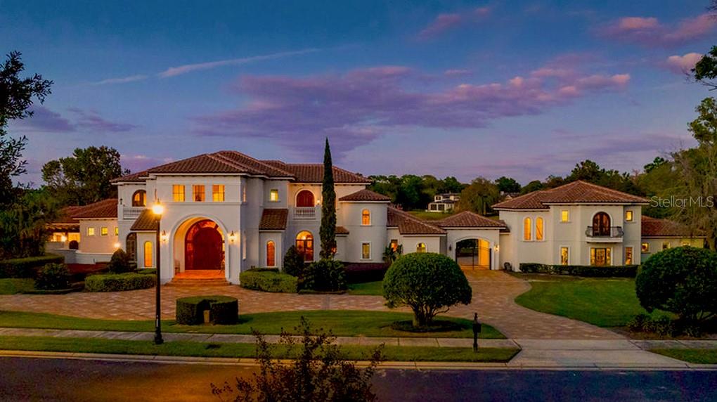 Experience the pinnacle of luxury living in this one-of-a-kind waterfront estate, ideally positioned on a double lot within the prestigious guard-gated community of Lake Markham Preserve, just minutes from Lake Mary, Longwood, Heathrow, and Sanford. This magnificent 5-bedroom, 7-bath, 6-car-garage residence spans over 2 acres of manicured grounds, offering a seamless blend of wellness, recreation, and refined sophistication.
A grand two-story foyer welcomes you with a sweeping double staircase, soaring ceilings, and breathtaking views of the sparkling infinity-edge pool that appears to flow directly into the lake. Exceptional craftsmanship defines every space, from the rich wood detailing in the executive office to the elegant finishes throughout the formal living and dining rooms.
The primary wing is a private sanctuary devoted to relaxation and health, featuring sea-salt walls and a sea-salt therapy room—a luxurious and restorative feature known to purify the air, improve respiratory wellness, and promote deep relaxation. French doors open from the primary suite and home office to a Tuscan-style courtyard, creating a tranquil retreat complete with landscaping and a soothing water feature. Inside the suite, enjoy a massage room, sauna, private fitness studio, and spa-inspired bath — your personal wellness haven.
The open-concept chef’s kitchen flows effortlessly into the spacious family room and entertainment wing, where you’ll find a game room with a private bowling lane, ideal for hosting and entertaining. Large windows and glass doors fill the home with natural light and frame sweeping views of the pool, courtyard, and lake.
The second floor of the residence continues the home’s sense of grandeur and comfort, offering a private retreat for family and guests alike. Upstairs, you’ll find three beautifully appointed en-suite bedrooms, each with its own luxurious bath and thoughtfully designed to provide privacy and comfort. The spacious theater room is perfect for movie nights or sporting events, creating a cinematic experience within the comfort of home. A large balcony stretches across the back of the home, offering sweeping views of the infinity-edge pool, lush grounds, and shimmering Lake Markham—the perfect setting for morning coffee or evening relaxation while taking in the tranquil lakefront panorama.
Outdoors, the resort ambiance takes center stage. A heated infinity-edge pool and spa, and summer kitchen create the perfect setting for gatherings and sunset dinners. A private boat dock with a covered lift provides direct access to Lake Markham, inviting peaceful mornings on the water or evenings spent boating under the stars. Recreational features abound, including a lighted basketball court, professional shuffleboard court, tiki hut cabana, all within fully fenced and landscaped grounds offering privacy and serenity.
A detached guest house provides comfort and independence for family or visitors, featuring its own living area, kitchen, and bath. Additional highlights include a custom wine cellar, whole-house generator, circular driveway, and ample guest parking.
Designed for the discerning professional who values both health and sophistication, this estate seamlessly combines wellness-oriented design, European-inspired elegance, and resort-style living in one breathtaking lakefront retreat — a true masterpiece where luxury meets longevity.