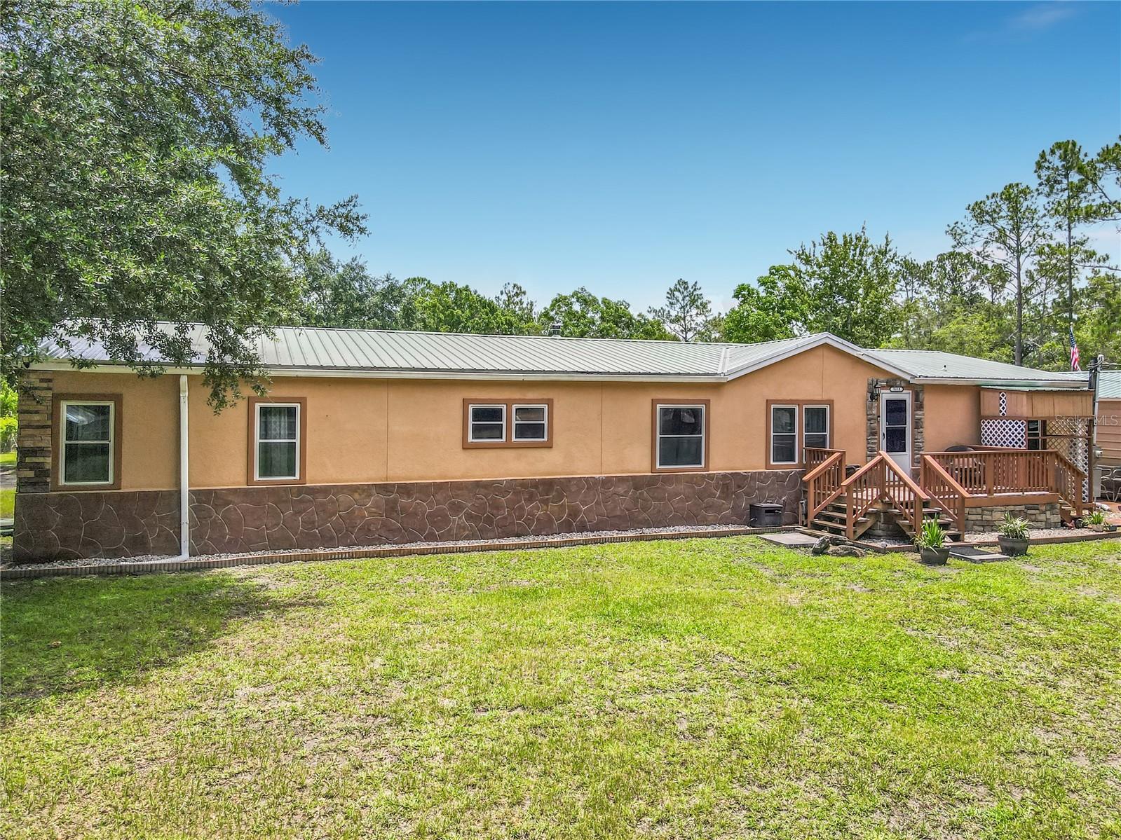 Welcome to your own private oasis where peaceful country living meets the convenience of being just minutes from the Atlantic Ocean and all that Palm Coast has to offer. This meticulously maintained property is completely enclosed with new 6-foot privacy fencing, plenty of room for your toys, equipment, and outdoor lifestyle.
Built by Palm Harbor, this high-quality 2,362-square-foot manufactured home features durable brick stucco construction and a metal roof, combining long-lasting quality with timeless curb appeal. The property also includes an insulated two-car garage, an enclosed barn perfect for trailers or additional storage, a stone driveway, one convenient walk-through gate, and two oversized 15-foot truck gates for easy access.
Step outside and enjoy your own backyard retreat featuring a heated above-ground pool, a new wraparound deck, and a charming gazebo—perfect for entertaining family and friends or relaxing after a long day.
Inside, you'll find a spacious and thoughtfully designed floor plan with 4 bedrooms, 3 full bathrooms, 2 separate living areas, and a dedicated fitness room complete with Nautilus weight equipment. The recently updated kitchen is a chef's delight with granite countertops, an LG French-door refrigerator, electric range, and plenty of workspace. Wood laminate flooring flows throughout the kitchen, dining area, laundry room, and bathrooms, while luxurious wall-to-wall carpeting adds warmth and comfort throughout the living spaces.
The oversized primary suite offers a spa-like bath complete with a garden tub and Corian countertops. Additional features include a washer and dryer, three separate central A/C systems (two 5-ton units and one 1.5-ton unit) for maximum comfort, a 60-foot well with water purification system, modern residential-style windows, storm tie-downs, and a metal roof re-roofed in 2019.
As an incredible bonus, the sale includes a 2019 Forest River 24-foot travel trailer that has only been used three times, along with several tractors, making this a truly unique, move-in-ready opportunity.
If you've been searching for privacy, space, quality construction, and an unbeatable location just minutes from beaches, shopping, dining, and Palm Coast, this one-of-a-kind property is ready to welcome you home. Schedule your private showing today!