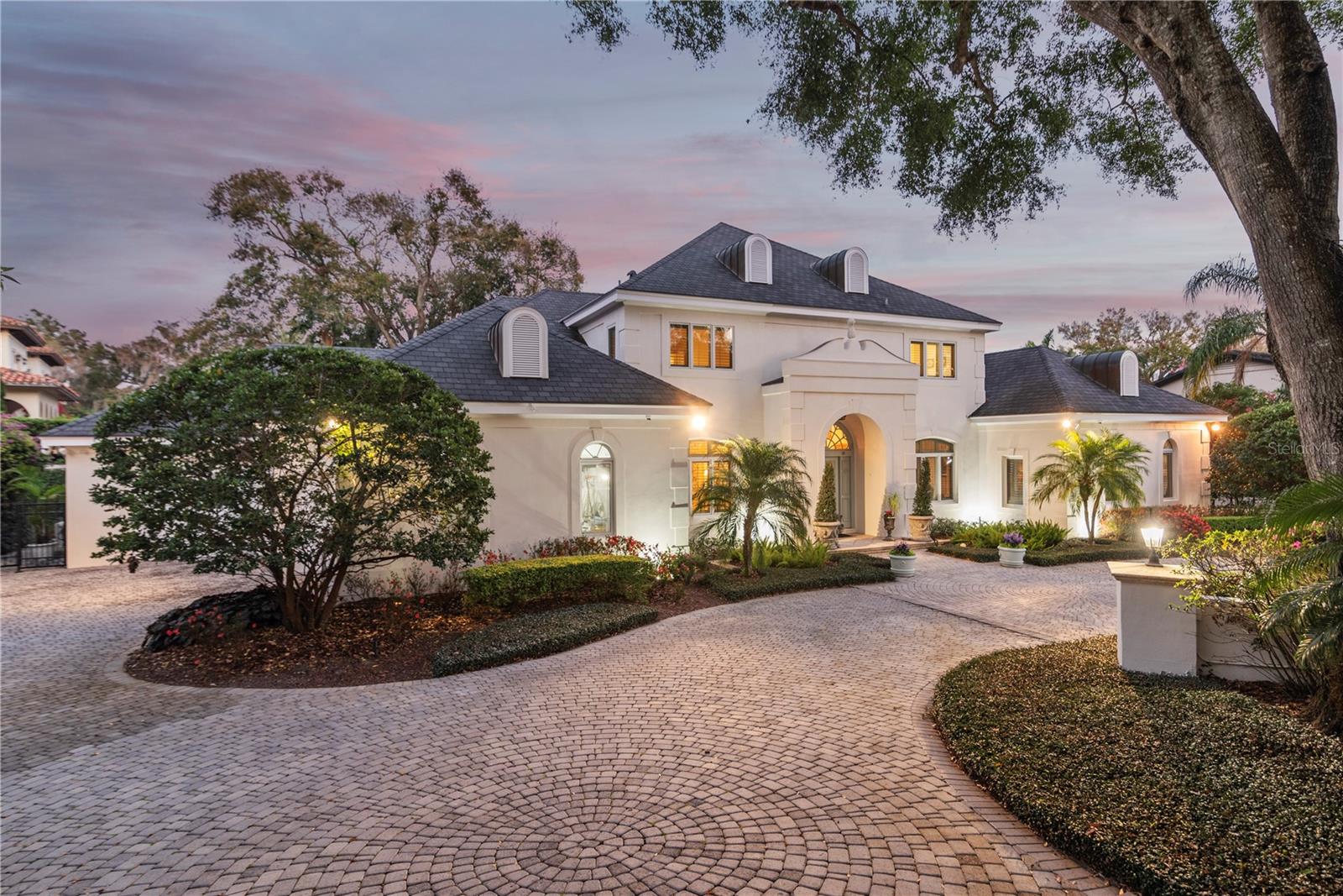 Stunning Lakefront Estate in the Heart of Delaney Park- Welcome to this exquisite lakefront estate on the shores of Lake Lancaster, where timeless elegance, modern comforts, and an unbeatable location come together. Nestled on a rare, sprawling half-acre lot in the heart of Delaney Park, this residence boasts a rare and generous piece of downtown real estate. As you arrive, the circular driveway and lush landscaping set the tone for the grandeur within. A three-car garage with additional golf cart parking provides convenience, while the stately foyer welcomes you with hardwood parquet and marble floors, a custom staircase, intricate crown molding and an abundance of natural light. Designed for both entertaining and everyday living, this home features a gracious dining room with elegant columns, a sparkling crystal chandelier, and chair railing. The spacious living room is the epitome of sophistication, boasting a stunning fireplace, custom built-ins, a wet bar, and four sets of French doors that open to a light-filled sunroom overlooking the lake. A cozy den with rich wood-paneled walls and built-in bookshelves offers a warm retreat. The chef’s dream kitchen is a masterpiece of style and function, featuring: White wood cabinetry & granite countertops, large island with drawer microwave, cooktop with pot filler & range hood, double Wolf built-in ovens & full Sub-Zero refrigerator & full Sun-Zero freezer, ice maker & walk-in pantry, Charming breakfast nook overlooking the lake. A spacious laundry room with lots of cabinetry and a sink  and two downstairs guest bathrooms offers added convenience. The primary bedroom wing is located downstairs and includes a large primary bedroom, a separate office, a large primary bathroom with a walk-in closet plus additional storage closets.  The primary suite is an expansive sanctuary, complete with a bay window framing breathtaking lake views. The primary bathroom features beautiful custom transom windows, dual sinks with a separate vanity area, a toilet closet and a walk-in glass-enclosed shower.  The tub was removed, but the plumbing is available to easily add a tub. Upstairs, an elegant grand staircase leads to three generously sized bedrooms, two full baths, and abundant storage. One of the bedrooms serves as a second primary suite, featuring a large walk-in closet and en suite bath with dual sinks, a tub, toilet closet and a walk-in shower. Additional features include plantation shutters, a whole house generator, irrigation, security system with cameras and termite bond. There is an abundance of storage closets, including two locked fireproof closets. Step outside to enjoy the serene lakefront lifestyle, perfect for fishing, kayaking, and paddleboarding. Located within walking distance to Delaney Park's baseball fields, tennis courts, and playground, and just minutes from Lake Davis, Lake Cherokee, Orlando Health/Winnie Palmer, SODO, Thornton Park, and the Dr. Phillips Performing Arts Center. Zoned for A-rated Blankner K-8 and Boone High School, this estate offers the best of downtown Orlando living. Don’t miss this rare opportunity to own a breathtaking lakefront estate in Delaney Park.