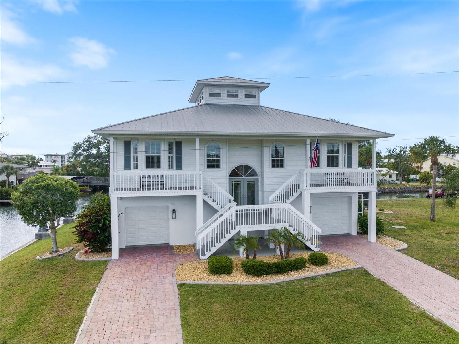 Experience the ultimate in gulf coast living with this beautiful 3-story Key West style home designed to capture a lifestyle defined by sun, water and effortless coastal luxury. Boating enthusiasts will appreciate the impressive waterfront setup complete w/2 covered boat lifts, davits and room for jet skis or skiff, providing effortless access to world-class fishing, sandy beaches, sunset cruises and deep-sea adventures. Enjoy direct canal-front access from this home, providing you quick passage with no bridges to the intercoastal and Gulf waters through Stump Pass. This custom retreat embodies the Florida lifestyle and features expansive living spaces w/vaulted ceilings filled with natural light and multiple decks to enjoy coastal breezes from all 3 levels. At the top, a charming crow’s nest offers a unique flex space perfect for a home office, reading retreat or creative space all enhanced by private deck access with a one-of-a-kind vantage point that offers peek-a-boo views of the intercoastal and is perfect for sunrise coffee or sunset cocktails. Extensively renovated and thoughtfully updated, this exceptional home is a perfect blend of coastal style and everyday functionality. Dual kitchens w/sleek quartz counters and stainless-steel appliances create the perfect setup for hosting or extended families. A split floor plan ensures comfort and privacy, while the elevator adds ease to daily living.  The spacious primary suite is a true retreat, featuring sliding glass doors that open to a screened lanai, creating a seamless indoor-outdoor connection. Dual w/i closets provide ample storage, while the luxurious en-suite bath offers a double-sink vanity, relaxing jetted tub, and a private water closet with a large walk-in shower. For added convenience, the suite also includes direct access to the generously sized laundry room.  The 2-car garage offers more than just parking; it’s designed for versatility. There’s additional room for a golf cart and includes a dedicated work bench for all your hobbies/projects. There’s no need to run upstairs for anything. The fully air-conditioned recreation space is designed for entertaining, complete with a convenient full bath and well-equipped kitchen featuring a refrigerator, microwave hookup, and dishwasher for easy cleanups. Step outside to your own private resort-style oasis, where a large sport pool offers plenty of room for everyone, along with an outdoor shower and expansive gathering spaces perfect for both lively entertaining and peaceful relaxation. Whether hosting guests or enjoying an evening under the stars, this outdoor space embodies the Florida lifestyle. This extraordinary property delivers the perfect combination of luxury, function and coastal charm-where every day feels like a vacation and the water is always within reach. Updates include but are not limited to new kitchens, carpeting, pool cage, composite decking, window treatments, lower bath refresh, Pool heater/Pump/Fascia tile, home mechanics, garage doors, boat lift and covers, motors for boat lifts, electrical to davits, most windows and exterior doors. Located in the quiet little enclave of Pine Cove with no HOA or Deed Restriction to hold you back. This home is set on a peaceful No-Through street adjacent to the Bill Coy Preserve offering water views both front and back. Experience nature at its finest w/eagles nesting close by, roseate spoonbills, herons & egrets often sited & manatees and dolphins grace the canal.