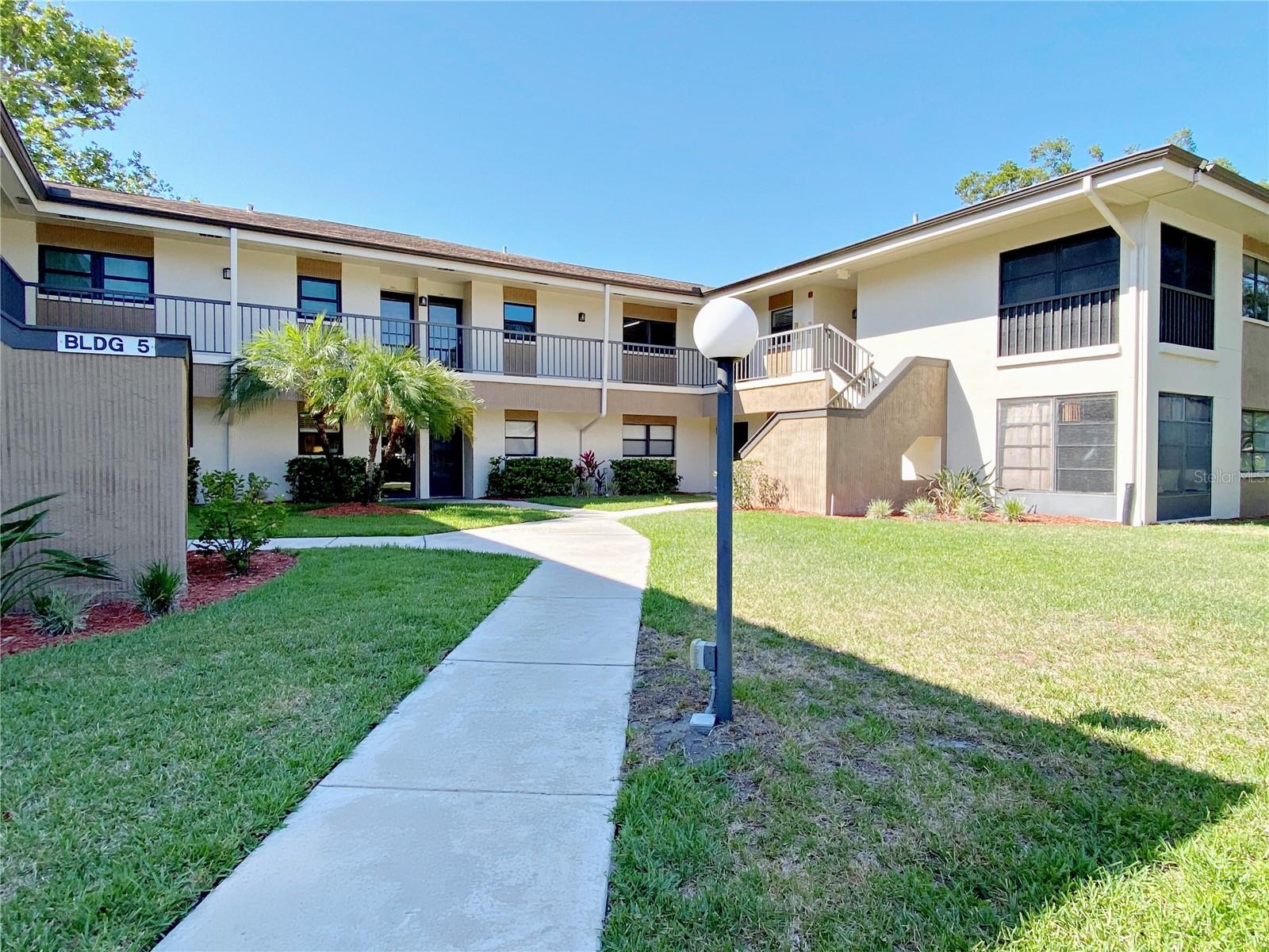 Come see this wonderful, first floor, corner, well-maintained condominium found in The Landings condo community in Palm Harbor. This small community was designed for effortless, low maintenance living. You will love this 2-bedroom, 2-bathroom, 1,000 sq. ft. condo. The home features ceramic tiles throughout the living space and laminate flooring in the bedrooms. The kitchen features light cabinetry, solid surface countertops, stainless appliances and a convenient passthrough to the dining area. The living room/dining room combination is nice open space. Off from the living room area there is lovely, enclosed porch with a picturesque view of the pond. Step out from the back porch and follow the sidewalk over to the pool and clubhouse for some sun and relaxation. The primary bedroom is spacious and has two built in closets. The primary bathroom features a walk-in shower. The hall bathroom has a tub/shower combination.  You will enjoy the convenience of the full-size indoor laundry closet. Parking is an assigned carport found right in front of the building. The Landings is located in north Pinellas County near restaurants, grocery stores, retail shopping and medical facilities. If you want to head out to the beach, Caladesi Island State Park is approximately 15 minutes away. Tampa International Airport is about 30 minutes away and St. Petersburg/Clearwater Airport is a 25-minute drive. Great location, easy living - make an appointment for a private tour today!