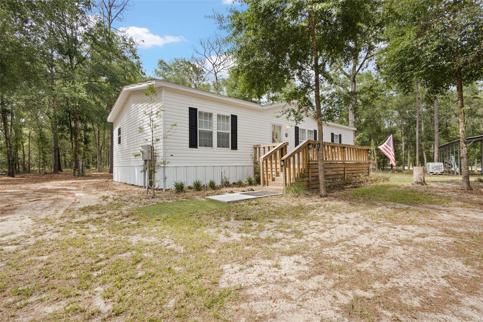 Under contract-accepting backup offers. Experience modern comfort and country charm in this beautiful 2024 Jacobsen Home located just outside the city limits of Bell, Florida. Situated on a paved road in a desirable no-HOA neighborhood, this move-in-ready 3-bedroom, 2-bath home offers the perfect blend of convenience, privacy, and modern living. Step inside to a thoughtfully designed open floor plan featuring 9-foot ceilings, tape-and-textured drywall throughout, luxury vinyl plank flooring, and bright, inviting living spaces. The quality finishes and elevated construction create a true residential feel rarely found at this price point. The heart of the home is the spacious kitchen, complete with ample cabinetry and counter space, a large walk-in pantry with abundant shelving, a deep farmhouse sink, and an oversized center island with seating for several people—perfect for casual dining, entertaining, or gathering with family and friends. The kitchen flows seamlessly into the main living area, enhancing the home's open and welcoming layout. The private primary suite serves as a relaxing retreat, featuring a generous walk-in closet and an impressive en-suite bathroom with a large low-profile walk-in shower and built-in bench seat for added comfort and convenience. Two additional bedrooms also feature walk-in closets, providing exceptional storage and functionality for family, guests, or a home office. A well-built front deck provides the perfect place to enjoy your morning coffee, unwind in the evenings, or take in the peaceful surroundings. Outside, the fenced property offers a beautiful balance of privacy and usability. The land remains partially wooded, providing a natural North Florida setting, while thoughtful underbrushing has created an open, park-like feel with plenty of usable space to enjoy. Adding even more value is the metal workshop, complete with 12-foot overhangs that provide excellent covered parking for an RV, boat, tractor, equipment, or multiple vehicles. Whether you're a hobbyist, need extra storage, or simply want protected parking, this versatile structure offers endless possibilities. Built in 2024, this like-new home combines modern construction, energy efficiency, and low-maintenance living. Located just outside the city limits of Bell, you'll enjoy the peace and freedom of country living while remaining conveniently close to local amenities. Don't miss this opportunity to own a beautifully appointed home with premium features, abundant storage, functional outdoor space, and the relaxed North Florida lifestyle you've been looking for.
