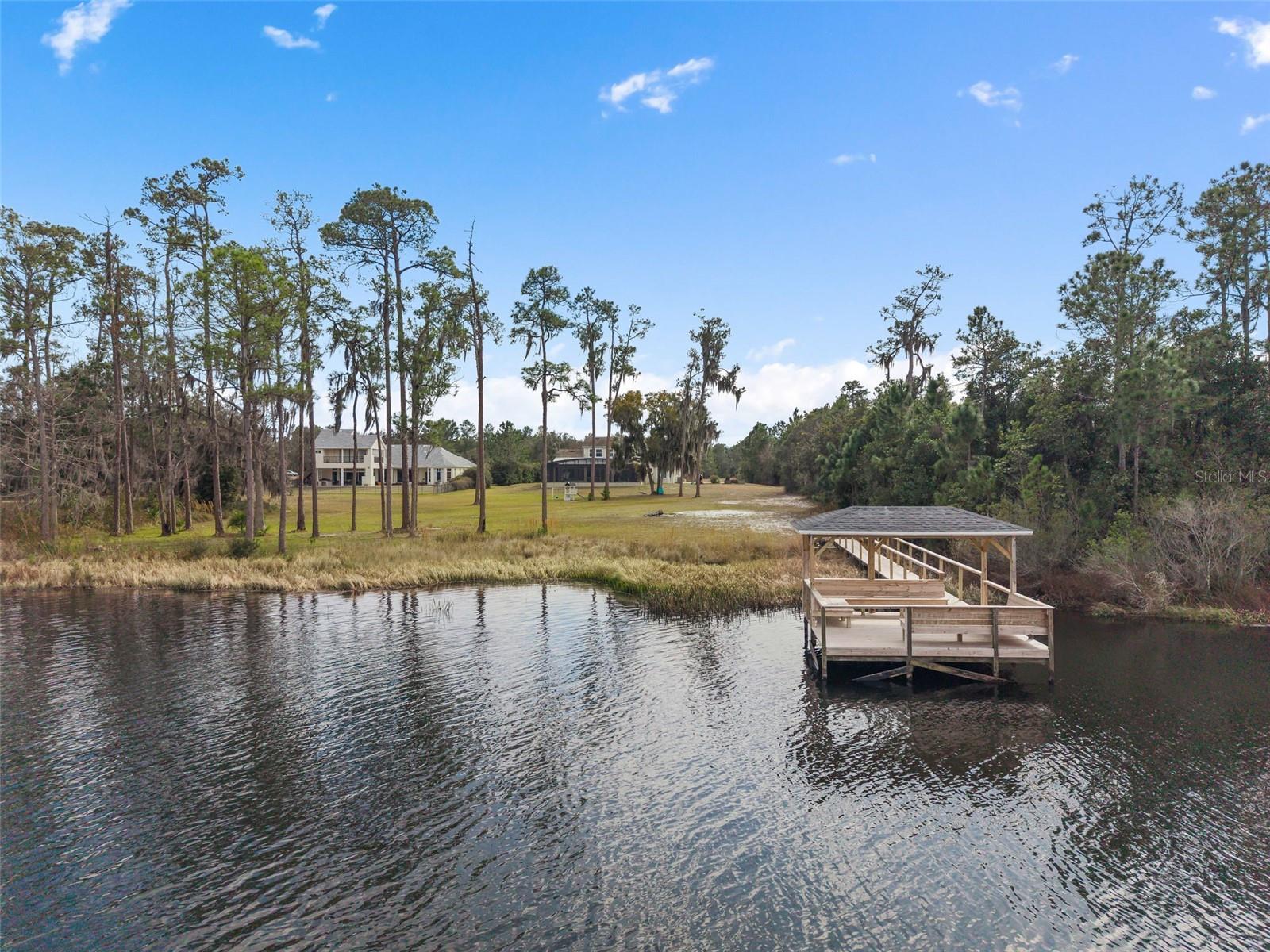 Virtually Staged. A rare opportunity to own five gated acres on a crystal-clear spring-fed ski lake just minutes from Lake Nona, this nearly 4,800-square-foot luxury residence offers over 160 feet of private shoreline, resort-style amenities, and an exceptional blend of privacy and convenience. Thoughtfully designed to maximize breathtaking water views, this one-of-a-kind property offers direct access to boating, wakeboarding, paddleboarding, kayaking, fishing, and year-round waterfront recreation.

Step outside to your own private resort featuring a brand-new (2025) custom saltwater pool with an expansive 25-foot sun shelf, an impressive 16-person spa, elegant marble pool decking, and a newly renovated private dock (2025)—creating the perfect setting for entertaining and embracing the waterfront lifestyle.

Ideally located just minutes from Lake Nona Medical City, the USTA National Campus, Narcoossee Road, SR 417, and Orlando International Airport, this estate offers peaceful waterfront living without sacrificing convenience.

Grand double glass entry doors welcome you into an elegant interior featuring soaring ceilings, double crown molding, 5-inch baseboards, and beautiful lake views from multiple living spaces.

The chef-inspired kitchen is designed for both everyday living and entertaining with quartz countertops, an oversized island seating six, custom cabinetry, a concealed pull-out pantry, double ovens, a gas cooktop with pot filler, a prep sink, premium stainless steel appliances, abundant electrical upgrades, and picturesque waterfront views.

The spacious family room centers around a cozy gas fireplace and opens seamlessly to the covered lanai, already pre-plumbed and vented for a future outdoor kitchen, creating effortless indoor-outdoor living.

Privately situated in its own wing, the owner’s suite offers panoramic lake views, direct lanai access, dual vanities, an oversized walk-in shower with dual shower heads, and a spacious walk-in closet.

Additional living spaces include a dedicated executive office, spacious upstairs loft, private downstairs guest suite, two additional upstairs bedrooms, and an approximately 700-square-foot bonus/flex room ideal as a home theater, game room, fitness studio, or potential fifth bedroom.

The oversized four-car garage features extended depth, climate control (heating and air conditioning), and motorized garage screens for year-round versatility.

The expansive five-acre homesite provides exceptional privacy, room to recreate, and endless possibilities for future enhancements.

Additional upgrades include dual HVAC systems (2021), whole-home water filtration (2025), reverse osmosis drinking water system, dedicated exterior connection for a future whole-house generator, energy-efficient Low-E windows, and a radiant heat barrier.

Offering five gated acres, over 160 feet of spring-fed lake frontage, resort-style outdoor living, and an exceptional location near Lake Nona, this extraordinary estate presents a rare opportunity to experience luxury waterfront living in one of Central Florida’s most desirable gated communities.