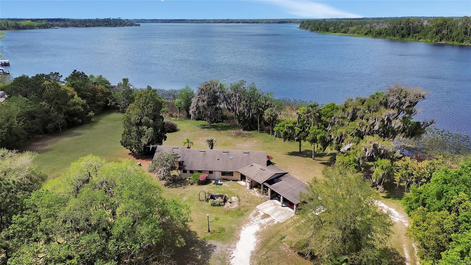 One or more photo(s) has been virtually staged. Welcome to an amazing property with the most amazing Sunsets overlooking magnificent Lake Dias. This is a great fishing, and water sports lake. This rare 16-acre retreat offers unparalleled privacy on an 800-acre lake shared by only a handful of neighbors with over 450 feet of waterfront, essentially makes a private playground for whoever secures this listing. The custom-built home features an open floor plan with beamed tongue and groove cathedral ceiling. The great room and dining room's sliding glass doors offer nature and lake views. The kitchen features a large island with Corian sink and countertop., nice cabinet space, closet pantry all open to the great room. The Primary Suite includes a large walk-in closet, a walk-in shower, and a dedicated studio space with cathedral ceilings and panoramic views. Massive 34 x 79 concrete block building, perfect for a workshop, car collection, or equipment storage. There is a dock and boat house with a lift. Equipped with a whole-house generator for peace of mind. A terrific location, 15 minutes to Award Winning Downtown DeLand, 30 minutes to Florida's greatest beaches.