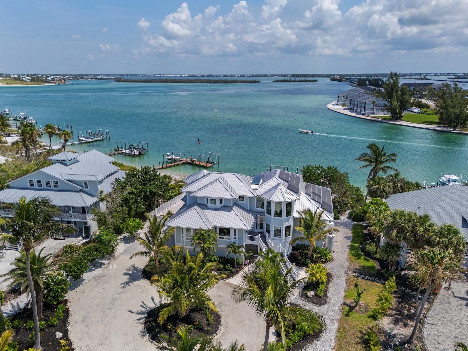 Coastal architecture, a modern Gulf Front masterpiece in Boca Grande, where bold design meets serenity. Designed by award-winning architect Gerald R. Maki and constructed by expert builder Jack Curley, this custom turnkey beachfront estate exudes commanding presence with clean lines, soaring spaces, and walls of glass, all set against a private Gulf-front backdrop. The main living level is a true spectacle, boasting 20-foot ceilings, custom woodwork, and a dramatic spiral staircase that sets the tone for the expansive great room. Multiple lounge zones and wraparound terraces seamlessly open to the outdoors, inviting guests to relax and unwind. A generous dining area, an updated kitchen with sleek cabinetry and modern finishes, and a layout designed for effortless entertaining and everyday luxury complete the living space. Upstairs, a glass-wrapped primary suite on its private level offers a lofted sanctuary with water-facing terraces, a sitting room, an office, and a spa-style bath that echoes the serenity of the setting. Two additional en-suite guest rooms provide privacy and balcony access, while the two-car garage with a dedicated golf cart bay ensures functional luxury. Even dedicated outdoor storage for fishing and diving gear is available, positioned for direct access to the water. Outside, the home underwent a transformative makeover in May 2025, featuring a modern tiled pool deck, a resurfaced and rebuilt heated pool and spa, lush native landscaping, and a rebuilt deepwater dock with two boat lifts. Just a short distance from your private, sandy beach. Sustainable and secure, the home is equipped with solar power and a rainwater harvesting system that supplies irrigation. Design-driven, Gulf-facing, architecturally significant, and turnkey perfection—this is one of a kind.