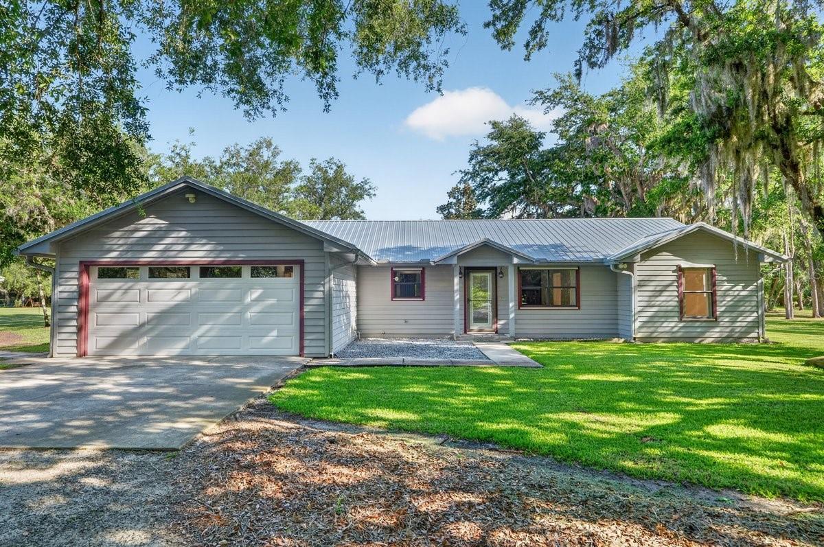 Situated on 2.5 private acres between US-1 and the river, this Edgewater property offers a setting that RARELY becomes available. Peaceful and shaded by sprawling oak trees, it’s the kind of space and privacy that’s hard to find this close to town and the water. Brand-new metal roofs on all buildings and fresh interior paint add to the home’s well-kept feel. Inside, cathedral ceilings, oversized bedrooms, generous storage, and wood-grain ceramic tile throughout create a comfortable, inviting atmosphere. The spacious eat-in kitchen opens naturally into the main living areas, making everyday living and entertaining feel effortless. Out back, the large tiled lanai overlooks the private backyard and offers the perfect spot to enjoy the breeze and quiet surroundings. The detached workshop is fully equipped with 220 electric, water hookup, heat and air, offering excellent flexibility for hobbies, storage, or workspace needs. A separate metal carport provides additional covered parking for boats, RVs, or extra vehicles. Additional features include a whole-house generator, gas fireplace, and irrigation system with a separate well. Properties with this much usable land, mature trees, privacy, and flexibility in such a desirable location between US-1 and the river rarely hit the market. This is the kind of property buyers wait for!