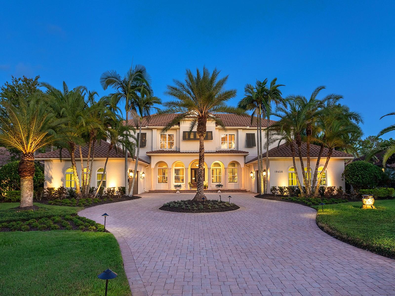 Built by Pruett Homes, this timeless estate embodies exceptional craftsmanship and thoughtful design, offering more than 7,000 square feet of living space on a beautifully landscaped 0.80-acre homesite in The Concession. A circular paver drive with a landscaped island and a barrel tile roof set a grand tone, while a welcoming front porch with stately columns leads to the double glass entry doors. Inside, architectural details include crown moldings, plantation shutters, oversized tile flooring, and soaring ceilings that enhance the home’s open, elegant aesthetic. The foyer introduces a refined entry with column accents and an art niche leading to the formal living and dining rooms. The living room centers on a gorgeous fireplace flanked by built-in shelving and opens through four-panel pocketing sliders to the lanai. A nearby wet bar features dolomite countertops with seating, wine storage, glass cabinetry, and a wine cooler—ideal for entertaining. The dining room showcases a tray ceiling with beams, designer wallpaper, and large picture windows. The enormous kitchen is perfectly designed for cooking and entertaining, highlighted by GE Monogram appliances, including a six-burner gas range with griddle, dual ovens, and a professional-grade refrigerator/freezer. Dolomite counters with bar seating, a center island, custom solid-wood cabinetry, a mother-of-pearl-accented backsplash, and an expansive walk-in pantry combine beauty and function. A breakfast nook with an aquarium window connects seamlessly to the family room, which opens fully to the lanai through dual pocketing sliders. A dedicated office with engineered wood flooring, crown molding, and surround sound provides a quiet workspace. Additional main-level spaces include a laundry room with abundant cabinetry, GE washer and dryer, and folding station, plus a half bath and a pool bath with custom tile finishes. The generous primary suite is privately positioned on the first floor, featuring engineered wood floors, a spacious, elevated seating area overlooking the pool, two oversized walk-in closets with wooden storage, and a spa-inspired bath with a jetted tub, frameless shower, dual vanities, and a makeup station. Upstairs, three expansive guest suites offer walk-in closets, plantation shutters, and en-suite or shared baths with custom tilework. The upper level also includes a spacious game and bonus room with a wet bar, granite counters, refrigerator, and microwave, plus a theater that seats 18 with tiered leather seating and a built-in bar. A large, covered terrace overlooks the pool and lanai, and an additional half bath serves the entertainment area. Outdoor living is equally impressive with a two-story screened lanai, heated saltwater pool and elevated spa with a cascading water feature, an outdoor kitchen with Stirling grill, fridge, sink, and seating, plus multiple covered lounging and dining areas. The fenced yard, landscape lighting, and lush tropical foliage complete the resort-style setting. In addition, four garage spaces—two on each side of the home—one side includes additional golf cart parking, while both feature ceiling fans, epoxy floors, and plantation shutters. Abundant storage throughout the home ensures functionality at every turn. The home also has a whole-house generator. The Concession, home to the PGA Tour World Golf Championship and Senior PGA Championship, is one of the most prestigious golf communities. Note: Windows and doors are NOT impact glass.