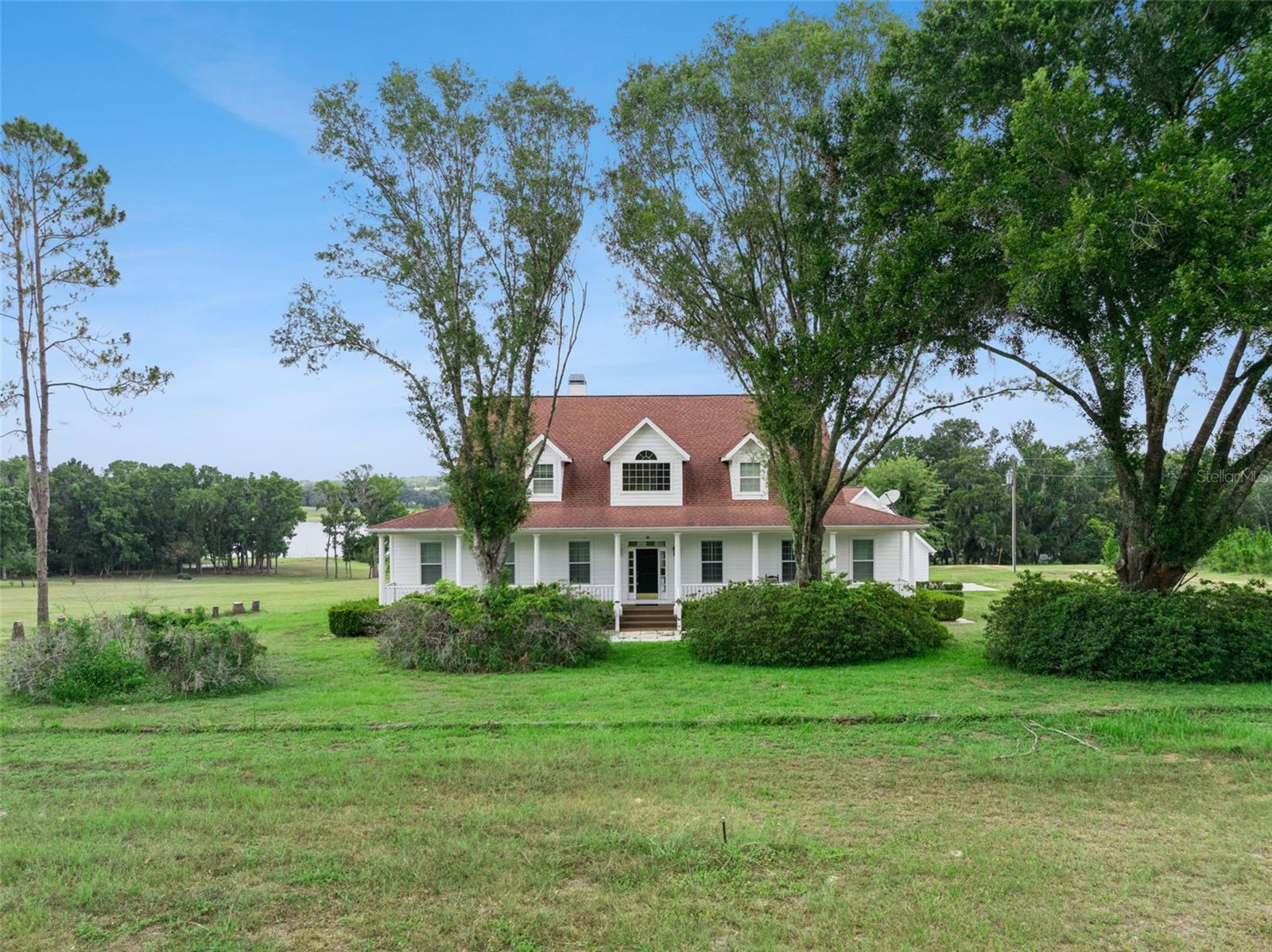 Welcome home to peaceful country living on the shores of Saint Clair Lake. Nestled on 5 picturesque acres zoned AG, this stunning farmhouse-style lakefront estate offers the perfect blend of timeless charm, modern comfort, and room to roam. With nearly 3,500 square feet of thoughtfully designed living space, 3 bedrooms, 3.5 bathrooms, and breathtaking views, this is the private retreat you've been dreaming of. AC's 2016 & 2021, Roof 2018.

From the moment you arrive, the lush landscape, mature trees, and classic wraparound-style front porch create an unforgettable first impression. Step inside the welcoming foyer where beautiful hardwood flooring and elegant crown molding flow throughout the main living areas of the first floor. To the right, the formal living room offers a warm and inviting space complete with plantation shutters that add both character and privacy.

Designed for both everyday living and entertaining, the open-concept family room features a cozy fireplace, custom built-in cabinetry, and an abundance of natural light pouring through an impressive wall of French doors that perfectly frame the backyard and lake beyond. The adjoining kitchen is equally impressive, offering generous quartz countertops, extensive cabinetry, bar seating, a pantry, double built-in ovens, a gas cooktop, and a spacious dining nook overlooking the tranquil backyard setting.

The thoughtfully designed split-bedroom floor plan places the owner's suite on the first floor for maximum privacy. This expansive retreat features two sets of French doors leading directly to the screened porch, allowing you to wake up to peaceful lake views each morning. The luxurious ensuite bathroom includes dual vanities, a relaxing walk-in soaking tub, a separate walk-in shower, and plenty of space to unwind. A convenient half bathroom is also located downstairs for guests.

Upstairs, both secondary bedrooms are generously sized and each enjoy the privacy of their own ensuite bathroom, making them ideal for family members or overnight guests.

Step outside through the wall of French doors to the spacious screened-in porch overlooking your expansive backyard, private acreage, and the sparkling waters of Saint Clair Lake. Whether you're enjoying your morning coffee, hosting family gatherings, or simply taking in the peaceful surroundings, this outdoor living space was designed to showcase the beauty of the property.

Perfectly positioned for those seeking peaceful country living without sacrificing convenience, this exceptional Brooksville location offers quick access to I-75, making commuting to Tampa, Wesley Chapel, Ocala, and Orlando remarkably easy. Outdoor enthusiasts will love being just minutes from the Withlacoochee State Forest, Withlacoochee State Trail, scenic rivers, horseback riding trails, parks, and countless opportunities for hiking, biking, kayaking, and wildlife viewing. Historic Downtown Brooksville offers charming local restaurants, boutique shopping, seasonal festivals, farmers markets, and the welcoming small-town atmosphere that has made this area one of Hernando County's hidden gems. Everyday conveniences including grocery stores, shopping centers, restaurants, and medical facilities are all just a short drive away.

Whether you're searching for a private family estate, hobby farm potential, or simply a peaceful lakefront lifestyle surrounded by nature, this extraordinary property is the one for you. Schedule your showing today!