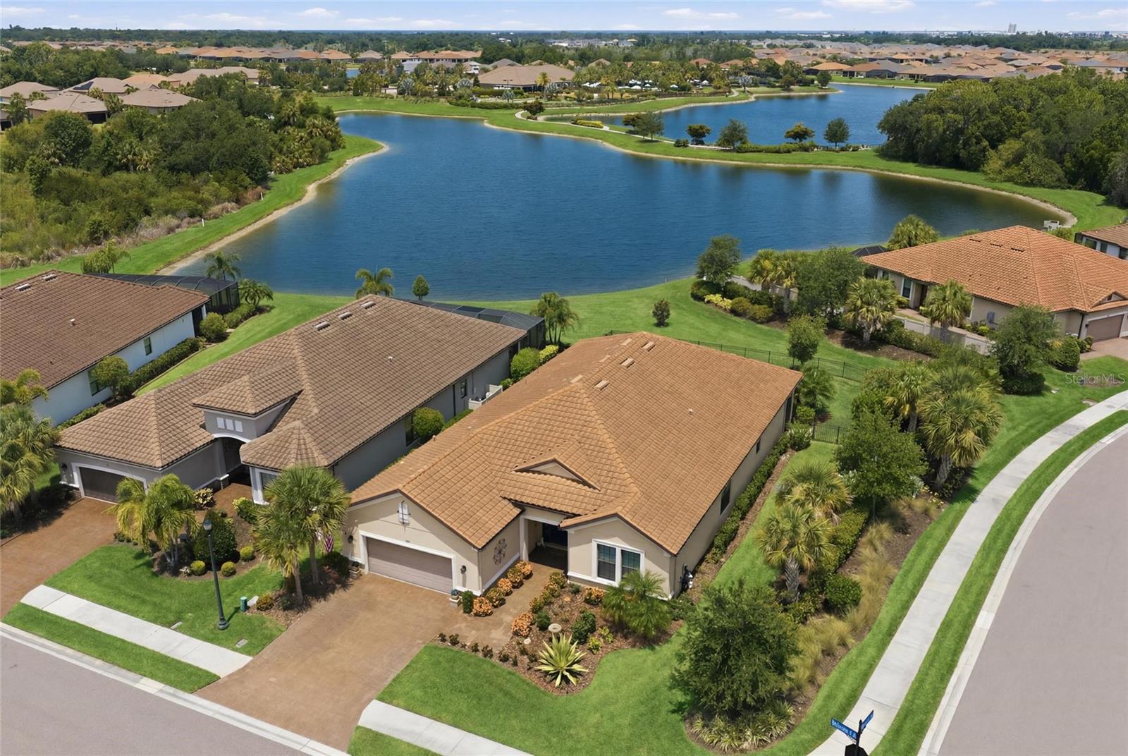 Experience elevated Florida living in this beautifully appointed Taylor Morrison Pallazio, perfectly positioned on one of the most desirable homesites in the community. Set on a rare oversized corner lot with a fully fenced backyard, this exceptional residence showcases breathtaking lake views and unforgettable sunset skies that create the perfect backdrop for everyday living.

Designed to embrace Florida's indoor-outdoor lifestyle, the expansive panoramic screened lanai seamlessly blends indoor comfort with the tranquility of the outdoors. Surrounded by lush tropical landscaping, this peaceful retreat offers an ideal setting for morning coffee, evening cocktails, or entertaining while taking in the sparkling water views. The lanai has also been thoughtfully prepped for future outdoor living with plumbing, gas, and electrical hookups for an outdoor kitchen, plus an additional electrical box already installed for a future pool and spa.

Inside, nearly 3,000 square feet of thoughtfully designed living space is enhanced by soaring 10-foot ceilings, abundant natural light, and an open-concept floor plan. The popular Pallazio design features three spacious bedrooms, a private study, and three full bathrooms, providing both functionality and flexibility.

At the heart of the home, the gourmet kitchen is designed to impress with an oversized center island featuring a prep sink, premium GE Café Series appliances, under-cabinet lighting, abundant cabinetry with convenient pull-out drawers throughout, and an open flow into the dining and great room perfect for both everyday living and entertaining.

The luxurious primary suite is privately situated at the rear of the home to maximize lake views and serenity. The elegant ensuite bath features dual vanities, an oversized walk-in shower, private water closet, and an expansive custom-designed walk-in closet that offers exceptional organization and storage. Guests will enjoy exceptional privacy with two generously sized guest bedrooms, including one with its own en-suite bath and another conveniently located next to a full guest bathroom.

Additional upgrades include full-house gutters, an epoxy-coated garage floor for a clean, polished finish, and numerous thoughtful enhancements that elevate both style and functionality throughout the home.

Located within the gated, resort-style community of Artisan Lakes, residents enjoy an exceptional maintenance-free lifestyle with HOA fees that include lawn care, landscaping maintenance, internet, and cable. The community's world-class amenities include a stunning clubhouse, heated lagoon-style pool and spa, resistance pool, state-of-the-art fitness and wellness center, tennis courts, pickleball courts, scenic walking trails, and a full-time Lifestyle Director coordinating year-round clubs, events, and activities.

Ideally located just minutes from I-75, you'll enjoy convenient access to shopping, restaurants, grocery stores, the future BayCare Hospital, popular local sports bars, and an easy commute to both Sarasota and St. Petersburg.

With its premium lakefront setting, rare fenced corner lot, spectacular sunsets, luxury upgrades, and one of Taylor Morrison's most sought-after floor plans, this is more than just a home it's the Florida lifestyle you've been waiting for.