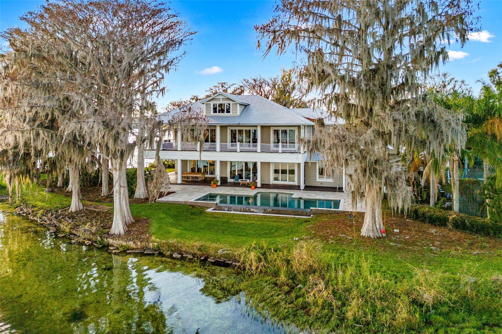 "The Point House" on lake Killarney.  Rarely available oasis, this spectacular lake front residence is positioned on a peninsula with .90 acres and over 440+ feet of lake frontage with unobstructed lake views to the south, west and east.   Constructed in 2012, this home features 6,000 living square footage (3,977 on the 1st level / 1,950 on the 2nd level), 4,000 sq. ft. of outdoor space, elevator, infinity pool, boat house and tennis court.  Main level offers 35 x 32 great room w/kitchen and dining, a separate dining area, 36 x 20 family room with bar/wine room, 4 bedrooms/ 3.5 baths, laundry room and 4 multi slider panel doors that open to wrap around patio with outdoor kitchen.  2nd floor offers a 2nd laundry room, lofted library, guest bedroom and primary bedroom with suite/lounge/built in wet bar and additional 4 multi slide panel doors that open to a wrap around balcony.   Experience the serenity and tranquility of old Florida under the majestic cypress trees beaming with wildlife/eagles/beavers and the ever changing landscape from sunrise to sunset.
